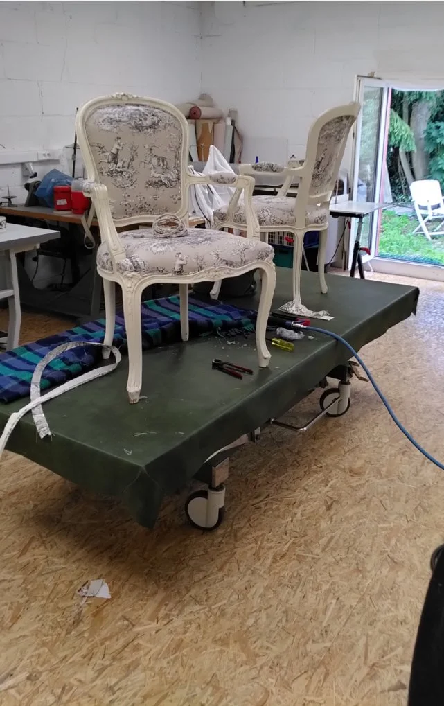 Een antieke stoel wordt gerepareerd op een werkbank met gereedschap en materialen, in het atelier van Katrijn De Waele tijdens een van haar workshops.