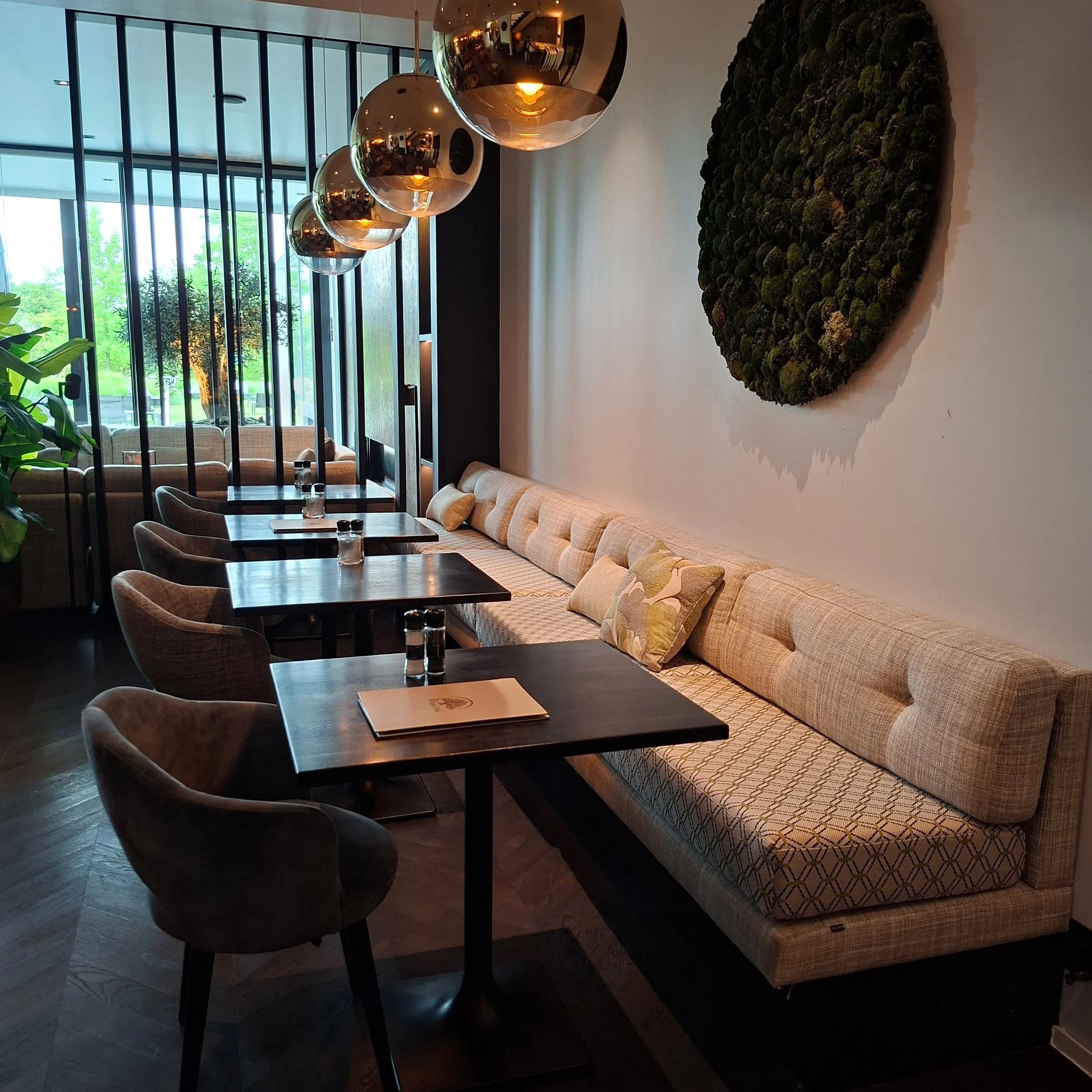 Binnenruimte van een modern restaurant met grote, door Katrijn De Waele geherstofferde, banken en tafels. Alles in een strakke, minimalistische stijl.