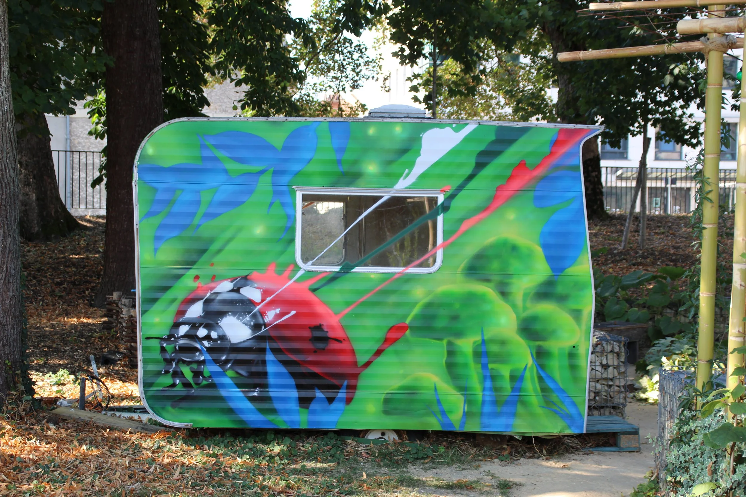 Peinture à la spray d'une coccinelle sur Caravane ancienne. Jardin du Centre culturel François Mitterrand. Périgueux.