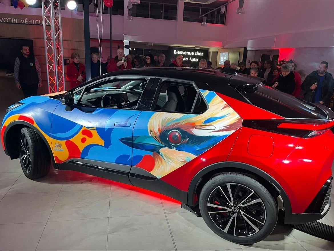Voiture électriquettes avec une peinture artistique, exhibition dans un salon automobile, foule de spectateurs à l'arrière.