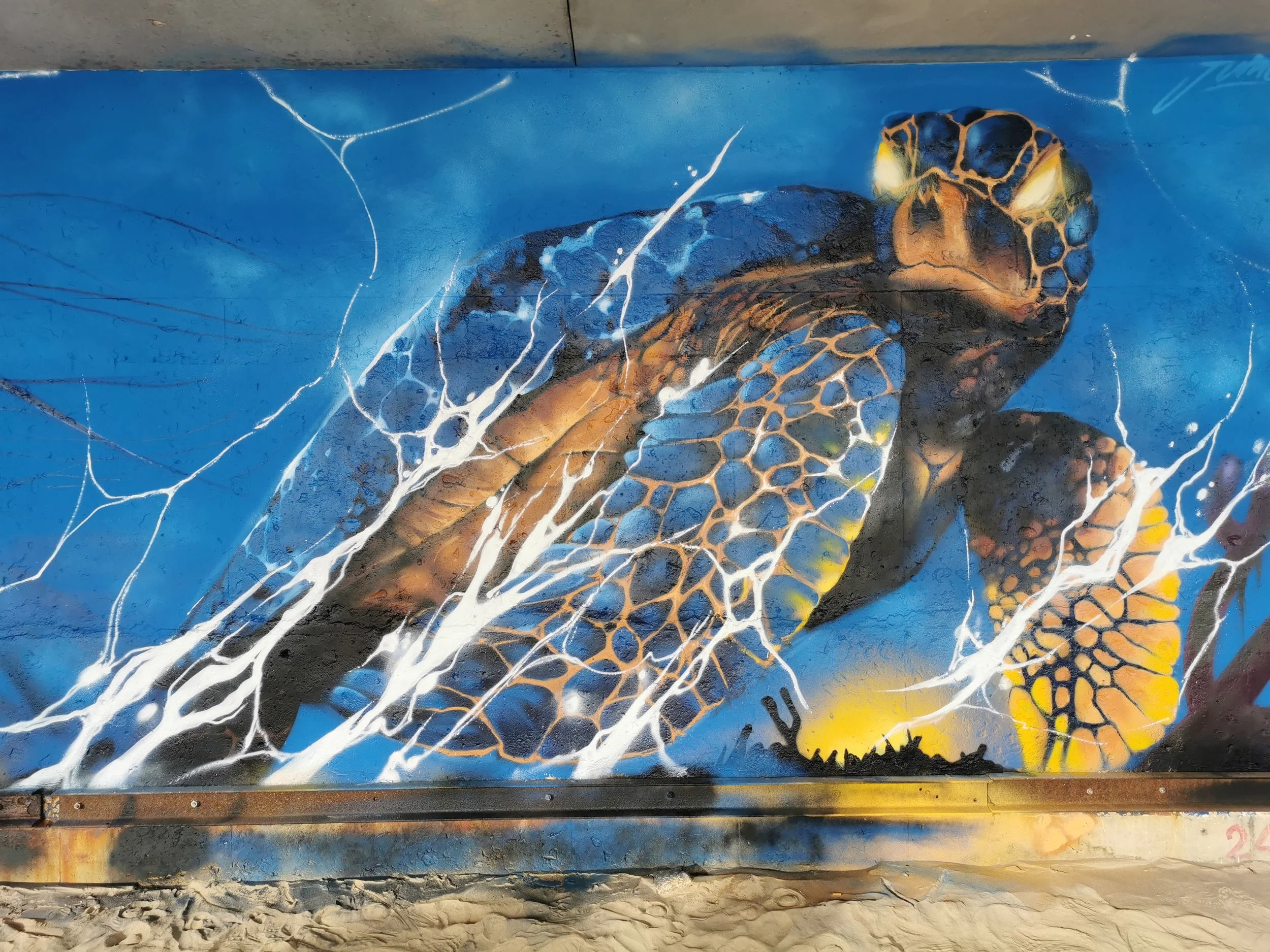 Peinture murale représentant une tortue de mer nageant dans l'eau avec des lignes d'écume autour dans un style artistique coloré.
