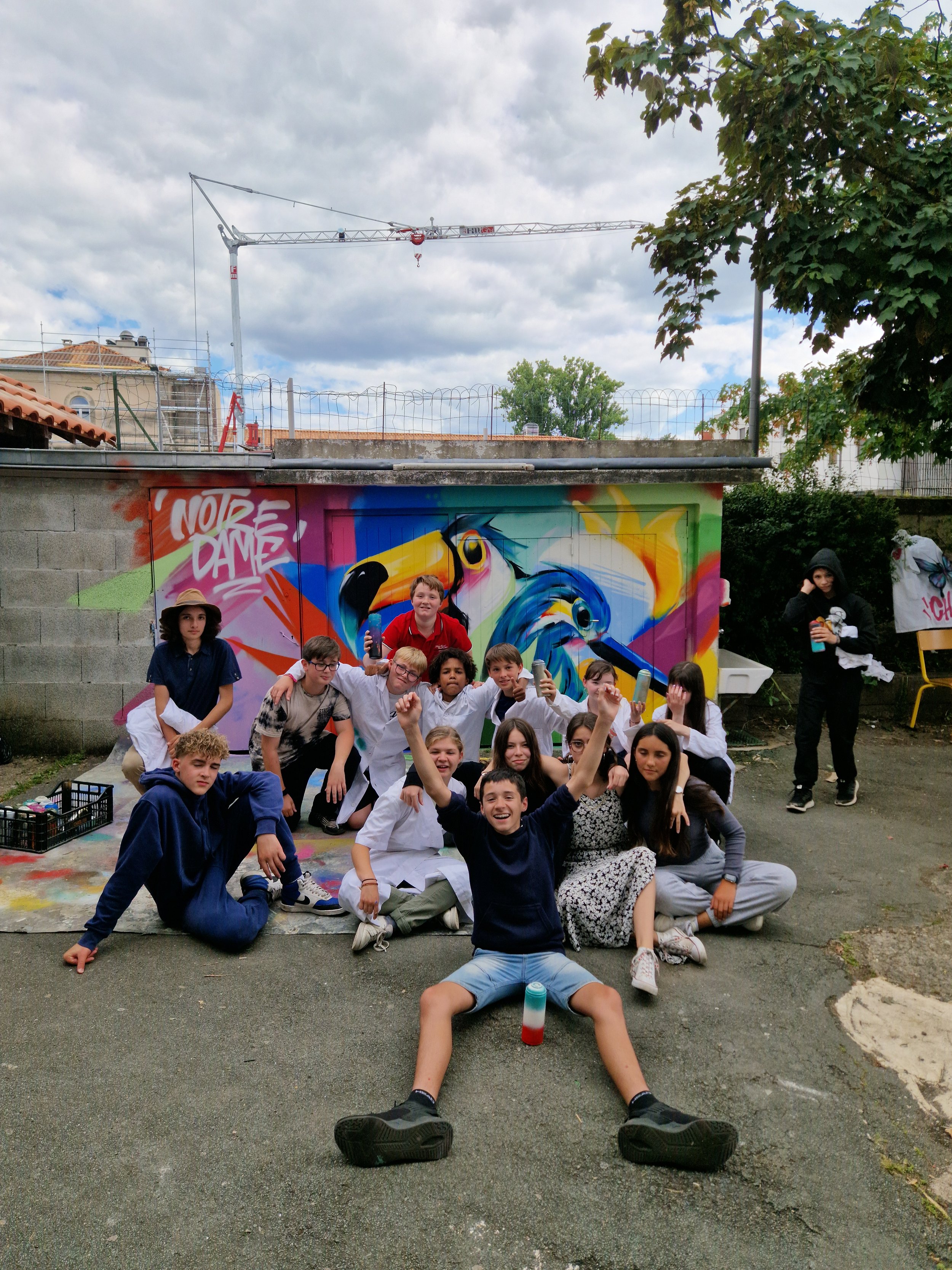 Groupe d'enfants posant devant un mur de graffiti coloré sur les toilettes du collége de Notre Dame à saint astier. peinture réalisé en atelier collectif par eggs58studio EGGS