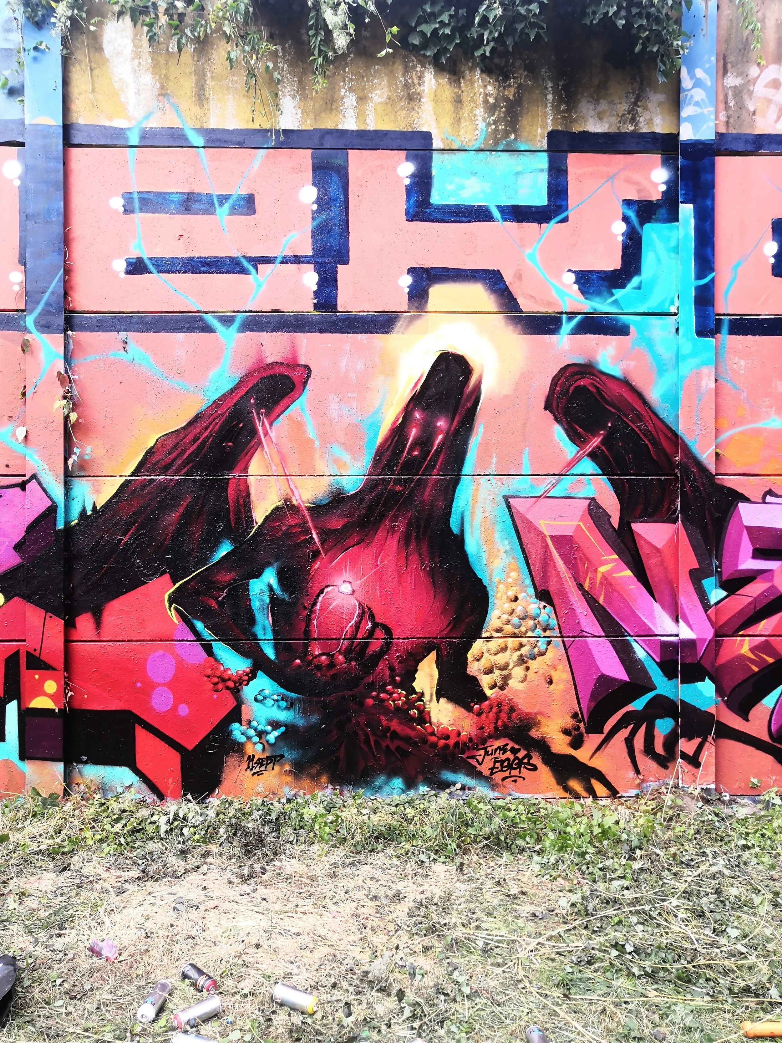 Une fresque de graffiti représentant deux mains noires avec des éclairs bleus et jaunes entre elles, avec un fond coloré de tons rose, orange, bleu, et violet, sur un mur en bois.