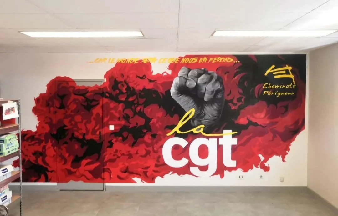 Fresque d'un poing fermé symbole de la lutte sociale, texte la cgt, syndicat francais de cheminots, un fumigéne rouge enrobe le mur.