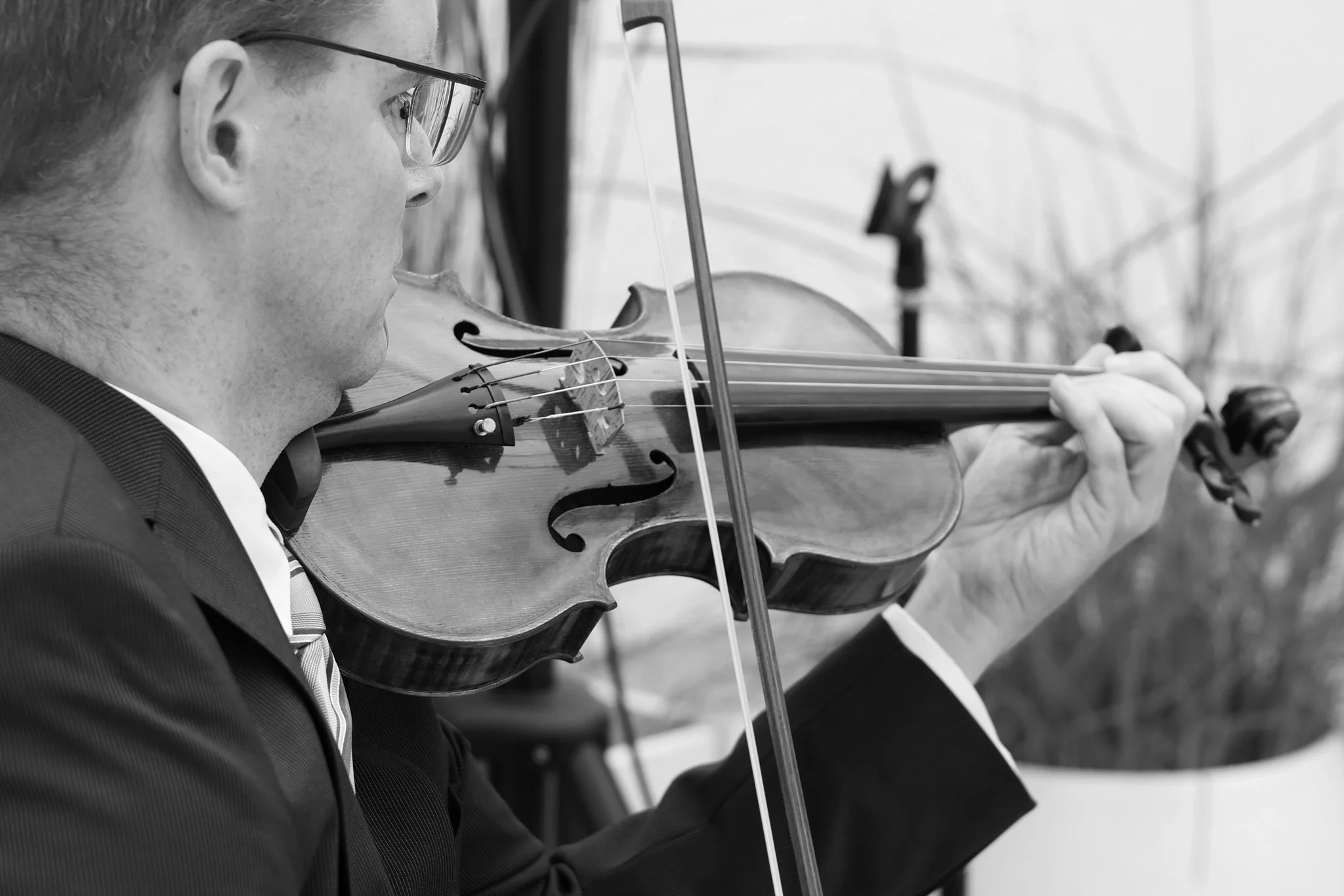 Geiger mit Brille spielt konzentriert Violine – ausdrucksstarkes Schwarz-Weiß-Portrait.