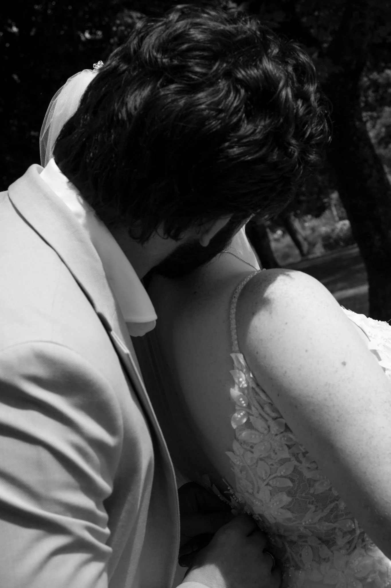 Schwarz-weiß-Aufnahme eines Brautpaares, das sich innig im Arm hält – emotionale Hochzeitsfotografie in natürlicher Umgebung.
