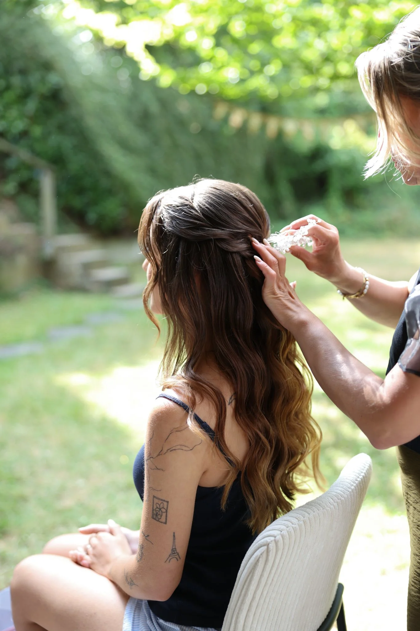 Braut beim Haarstyling im Grünen – entspannter Moment während der Hochzeitsvorbereitungen.