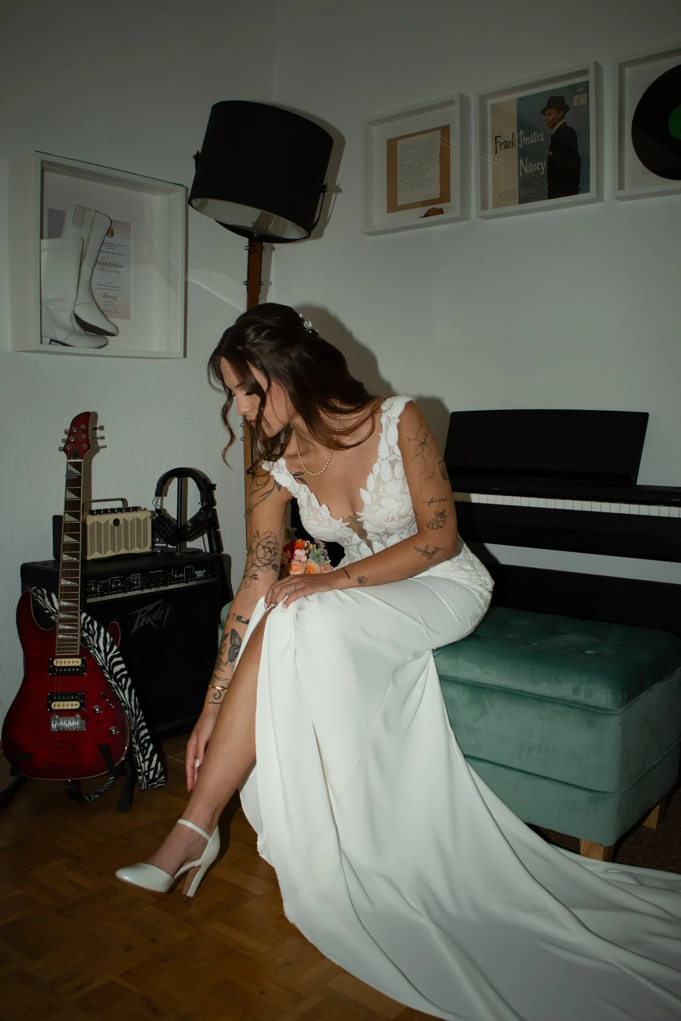 Braut zieht auf einem grünen Samtsofa ihren Brautschuh an – Getting Ready vor der Hochzeit.
