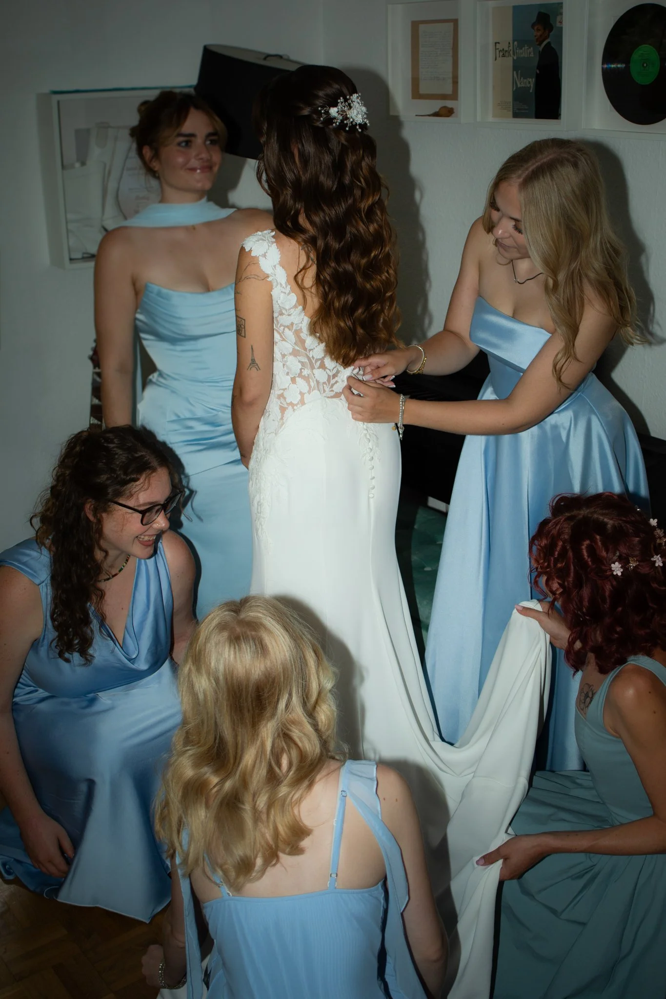 Brautjungfern unterstützen die Braut beim Anziehen ihres Hochzeitskleides.