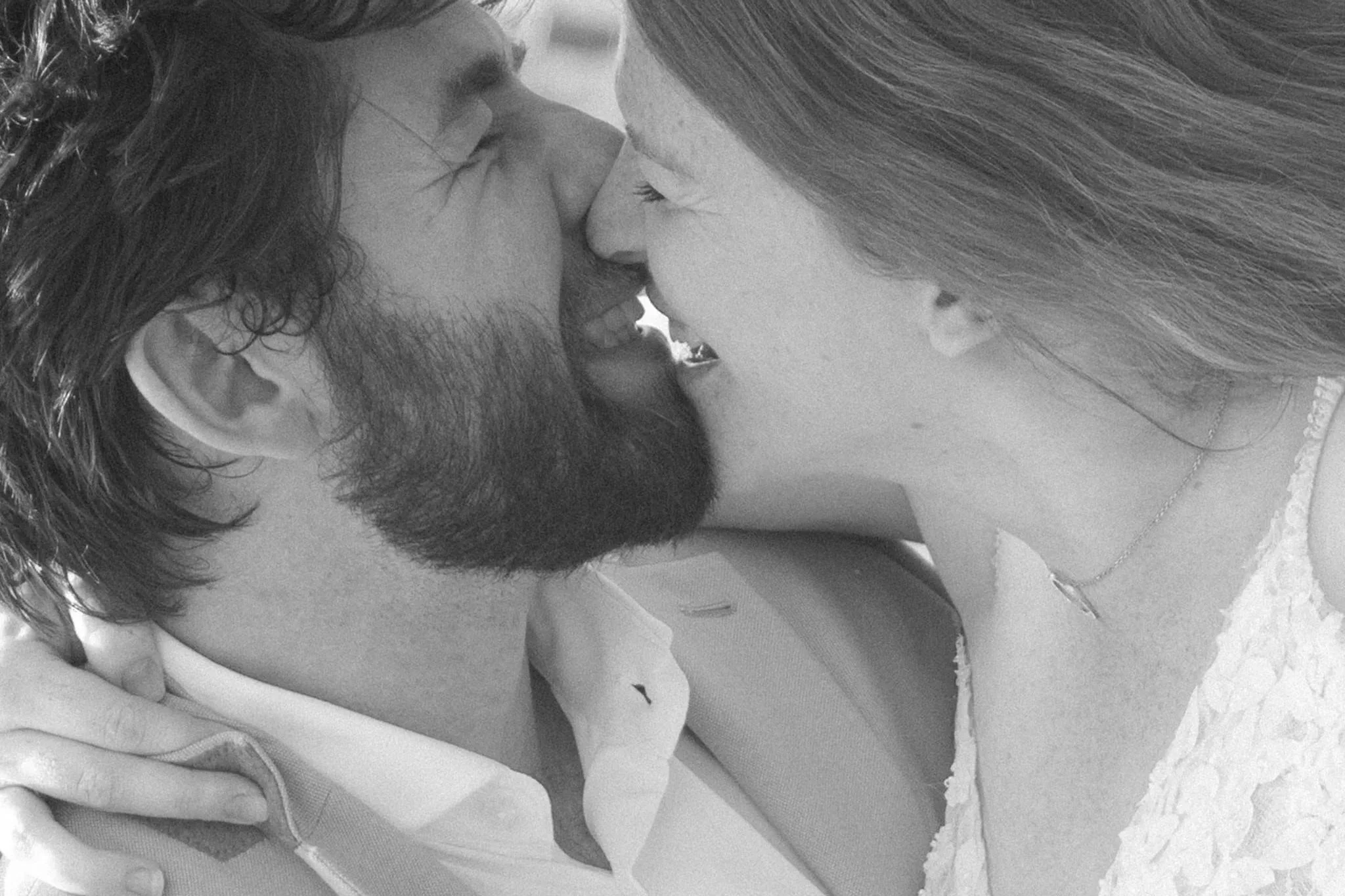 Schwarz-Weiß-Portrait eines Brautpaares, das sich lächelnd Stirn an Stirn berührt – intime und emotionale Hochzeitsfotografie.