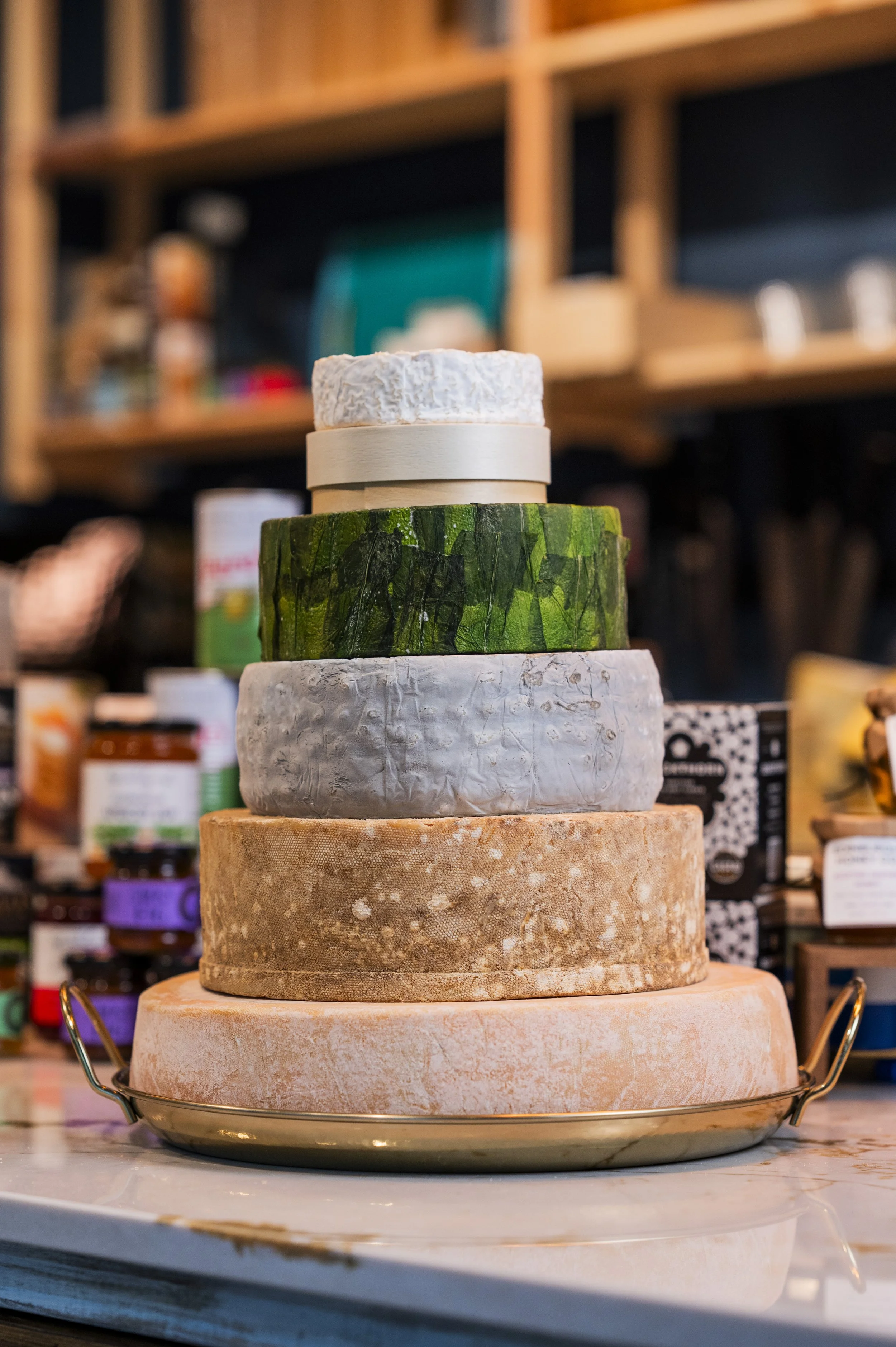Stacked cheeses of different colors and textures on a metal tray.