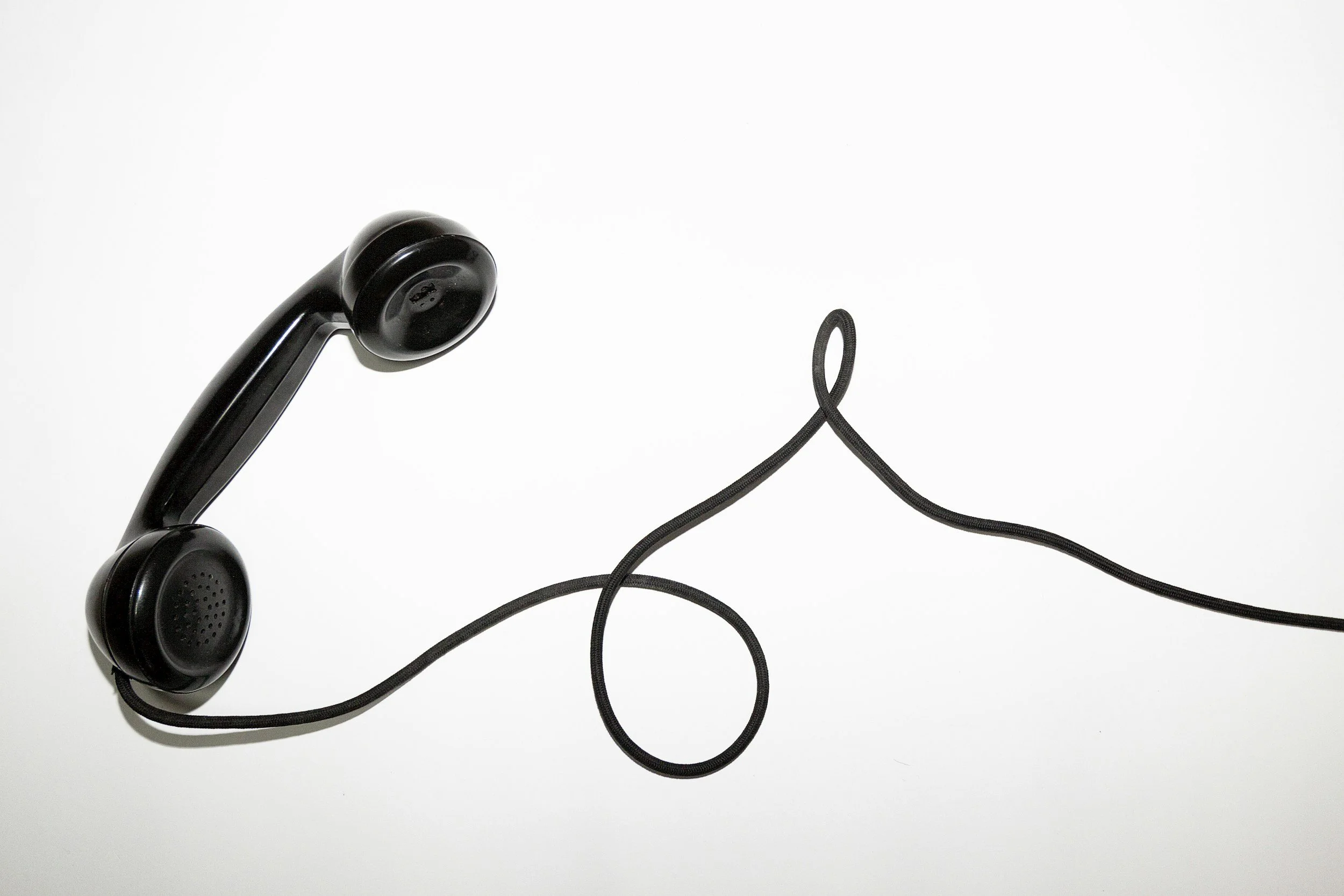 Black telephone handset with cord on a white background.
