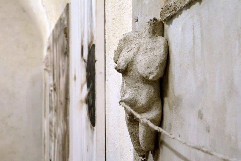 Statua di pietra di una figura umana dipinta di bianco, fissata emersa in un opera di alto livello emozionale