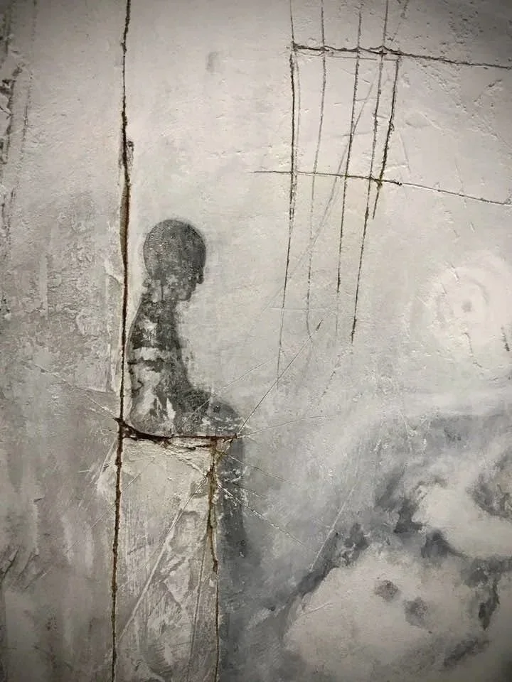 fiigura umana seduta, dipinta su parete di cemento con crepe e linee di rottura