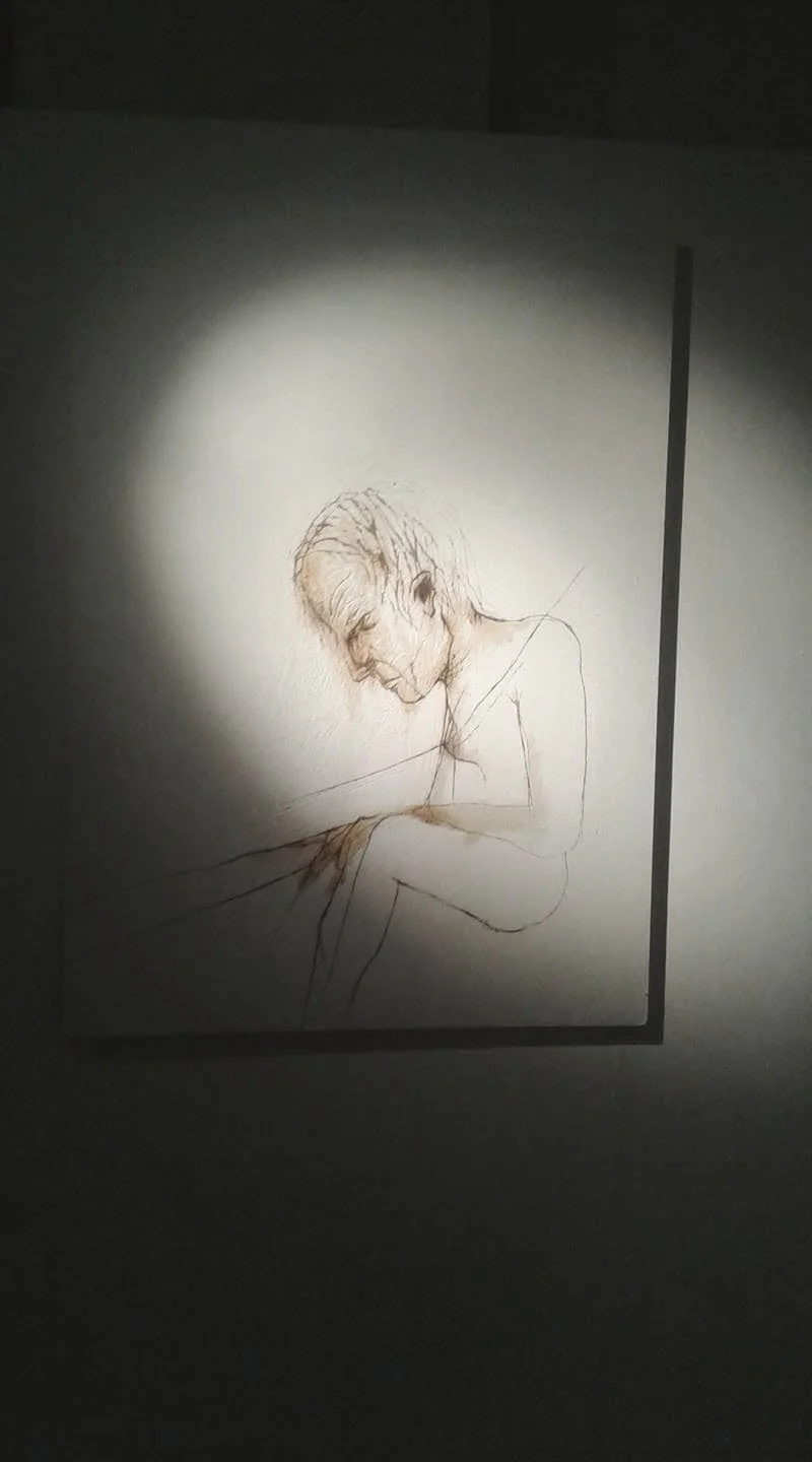 Disegno di una donna distesa, illuminato da una luce che crea un alone attorno a lei, realizzato con linee sottili e dettagli delicati.