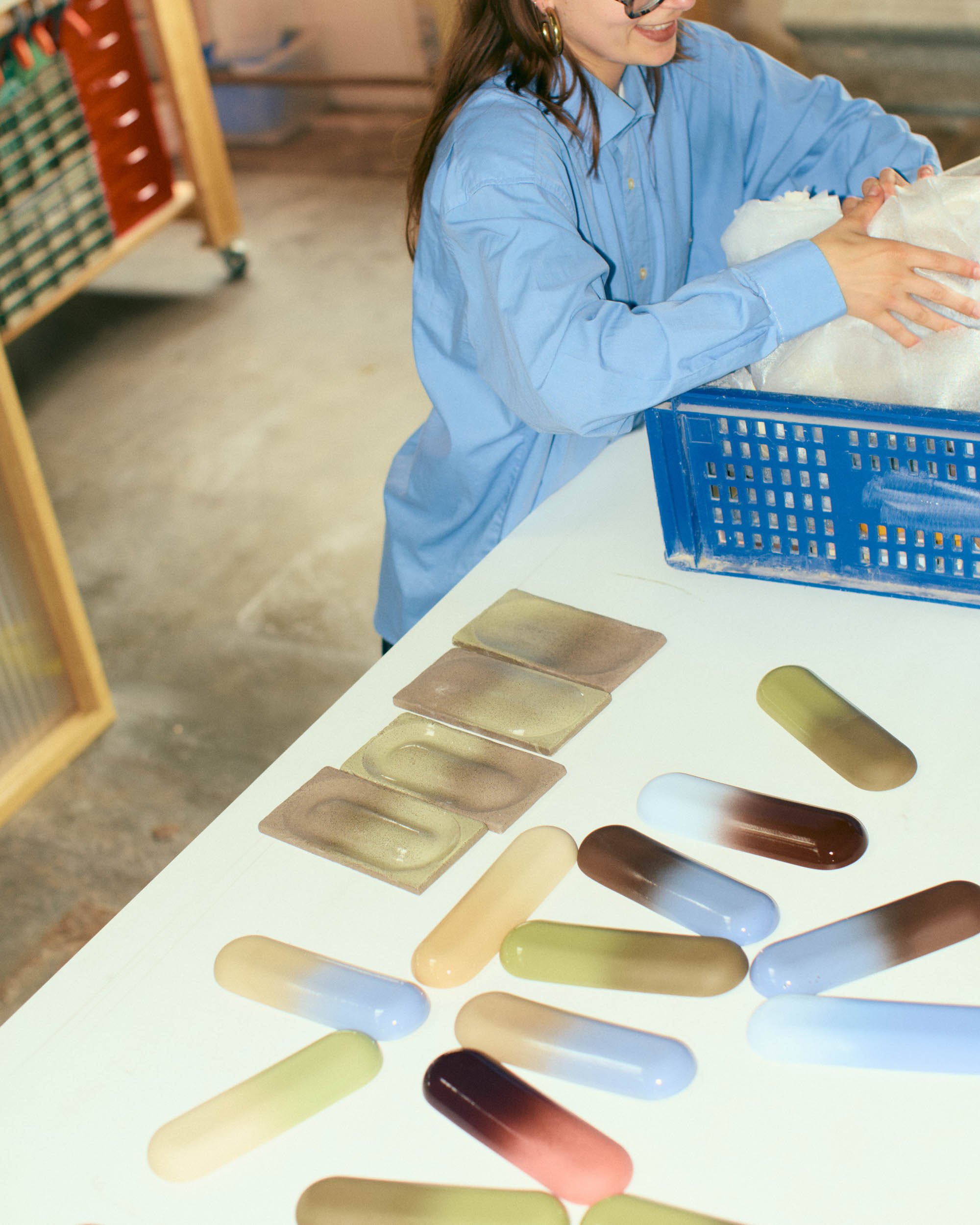 A woman in a blue shirt looking at color swatches on a white table
