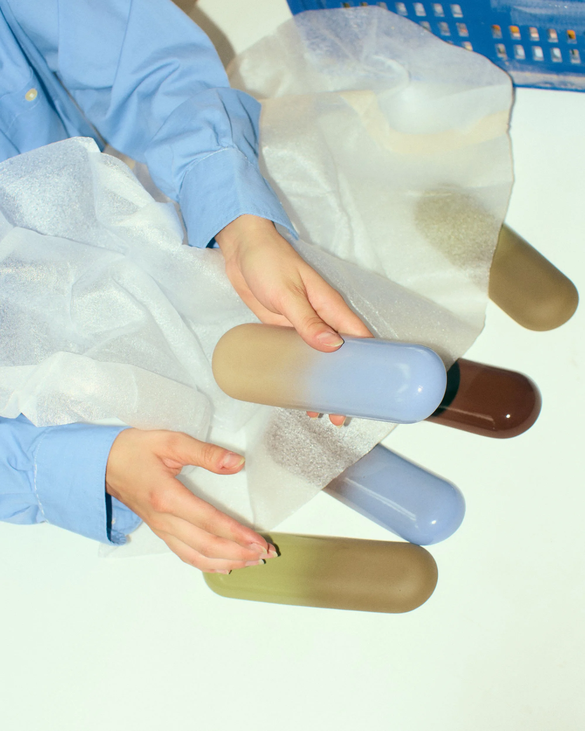 Person in blue scrubs holding a gray and brown object, with a blue basket and white foam padding on a white surface.