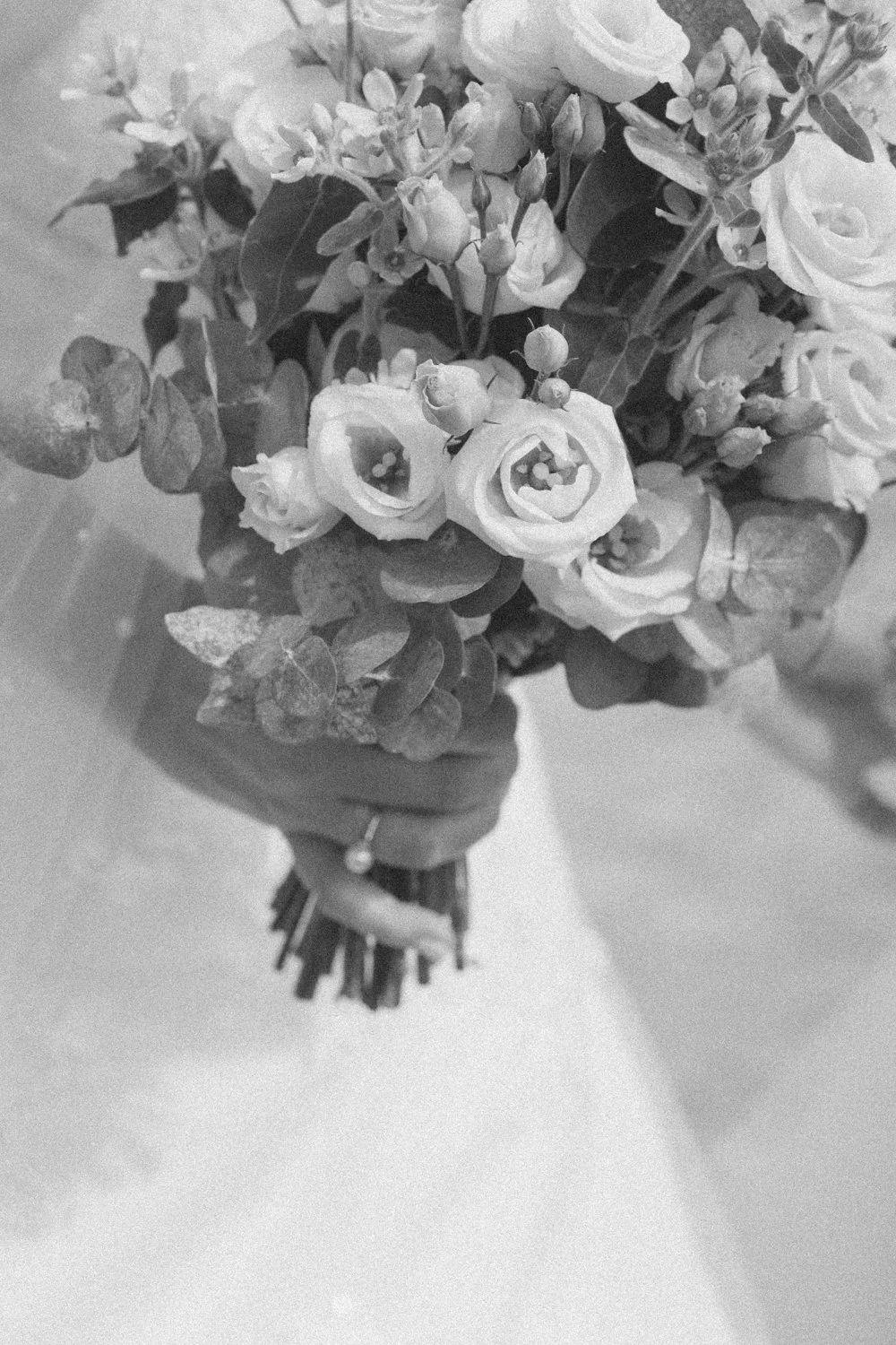 A person holding a bouquet of flowers, including roses, in a vase or wrapping.