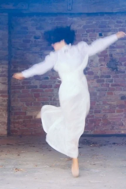 Una ballerina che danza in un ambiente industriale con pareti di mattoni