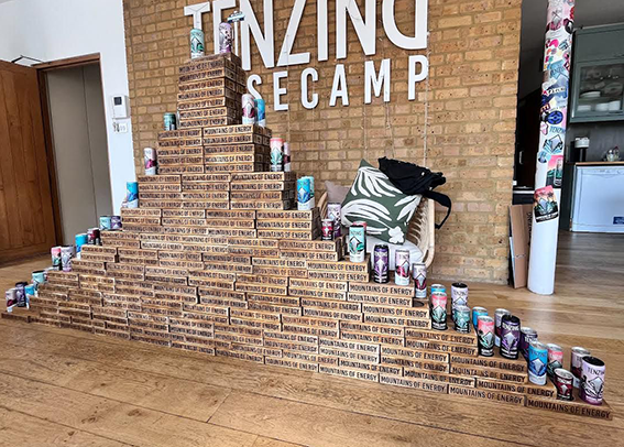 Eine Treppe aus Kisten mit der Aufschrift 'Mountain of Energy'. Über der Treppe hängen große Buchstaben, die 'TENERZING SE CAMP' bilden.