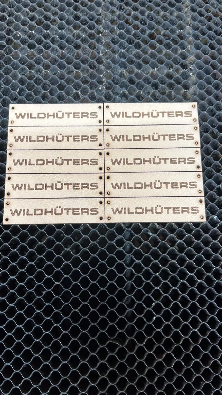 Mehrere Holzschilder mit der Aufschrift 'WILDHÜTERS' auf einem schwarzen Gitter.