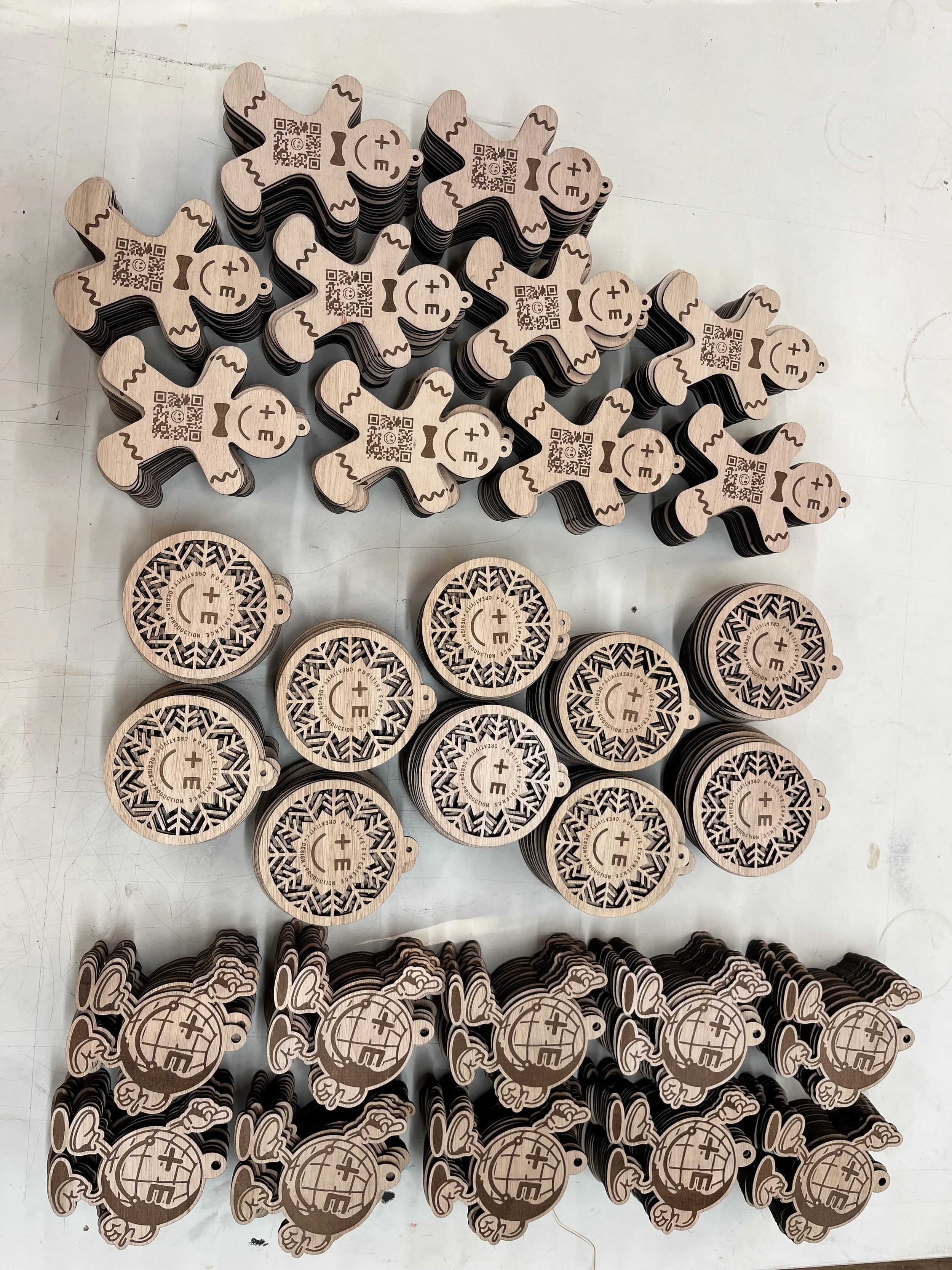 Mehrere Holz-Souvenirs in Form von kleinen Teddybären und Weltkugel-Designs, die anscheinend für ein Event oder eine Promotion hergestellt wurden, liegen auf einer weißen Oberfläche.