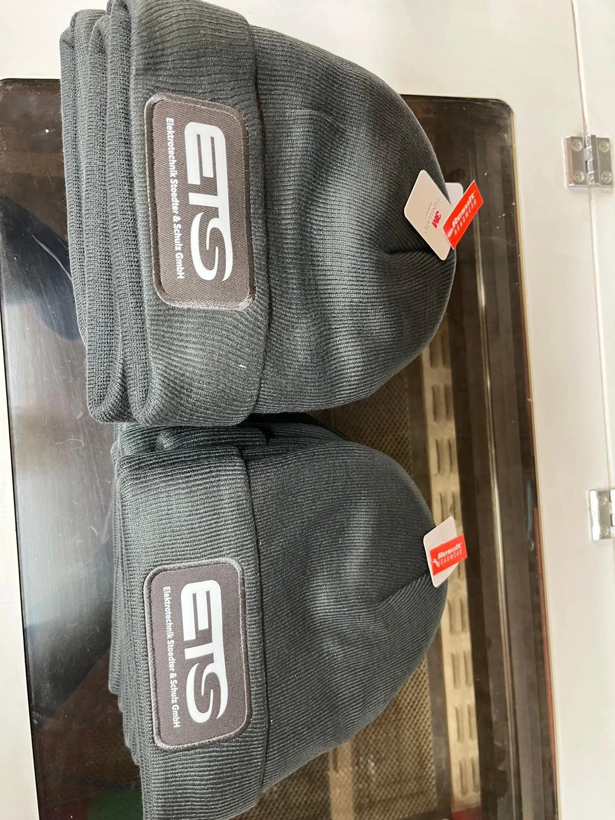 Zwei schwarze E-Scooter Helme mit Marke ESEE, auf einer Werkbank liegend, jeweils mit Aufklebern, einer mit Result Quality