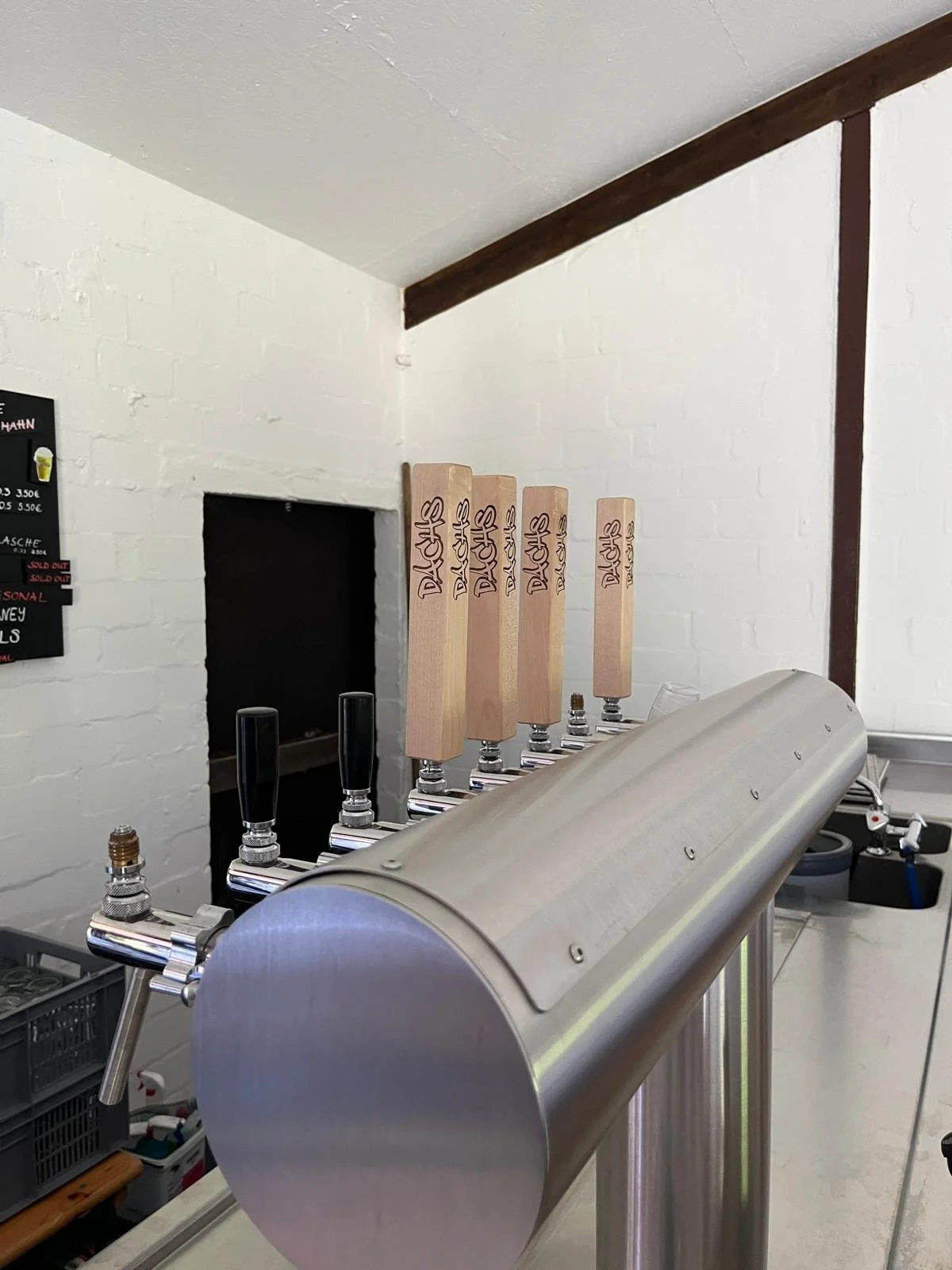 Mehrere Zapfhähne an einer Zapfanlage mit Holzgriffen, die auf einem Metallgehäuse installiert sind, in einer Bar oder Kneipe.