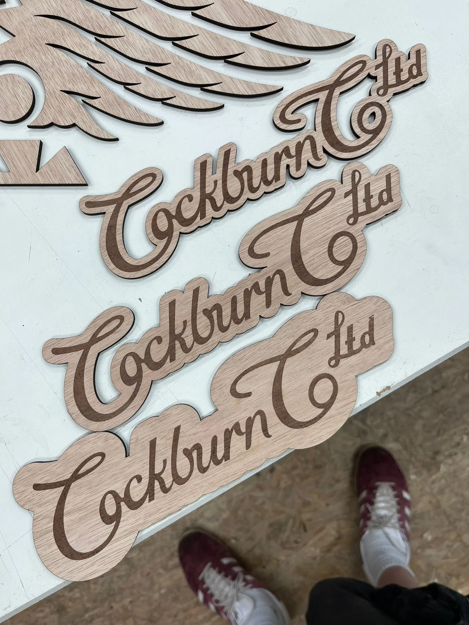 Holzschilder mit der Aufschrift 'Tacknound' in einer Reihe, auf einem weißen Tisch, zu sehen von oben aufgenommen.