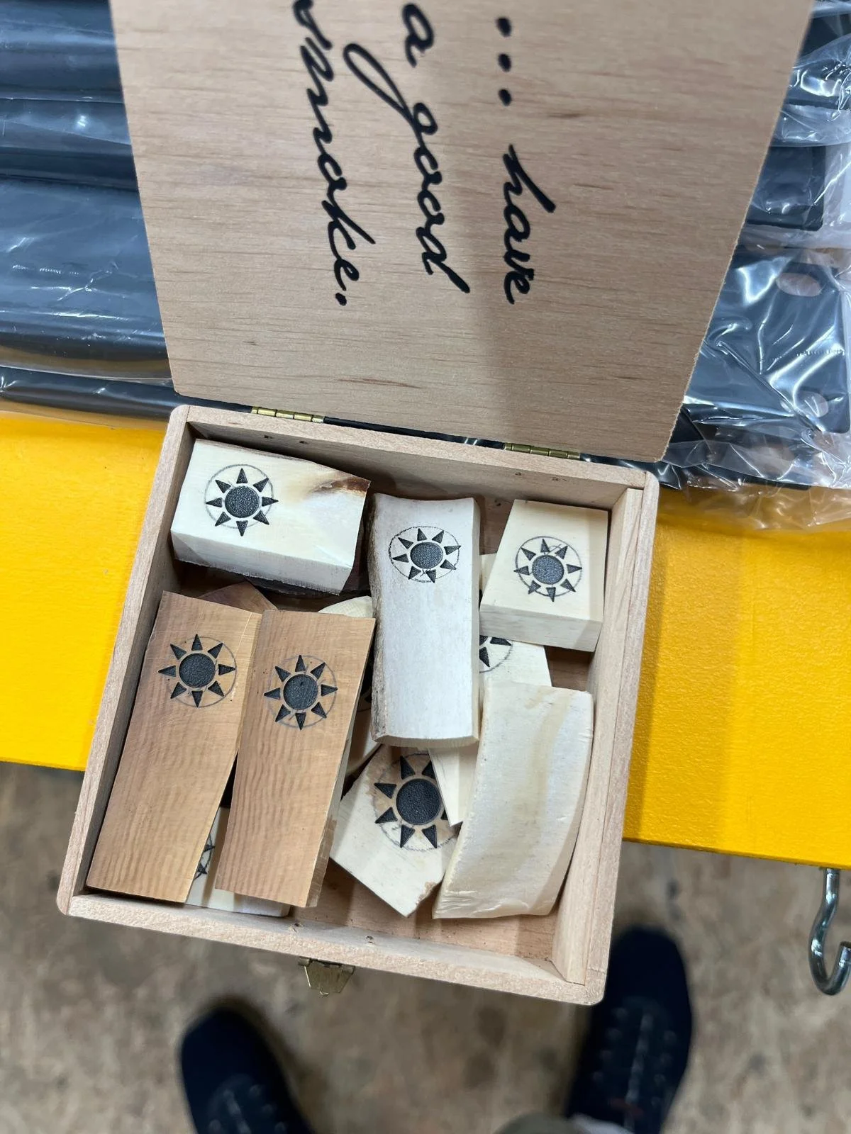 Holzstempel in einer Schachtel, mit einem Sonnen-Design, auf einem gelben Tisch