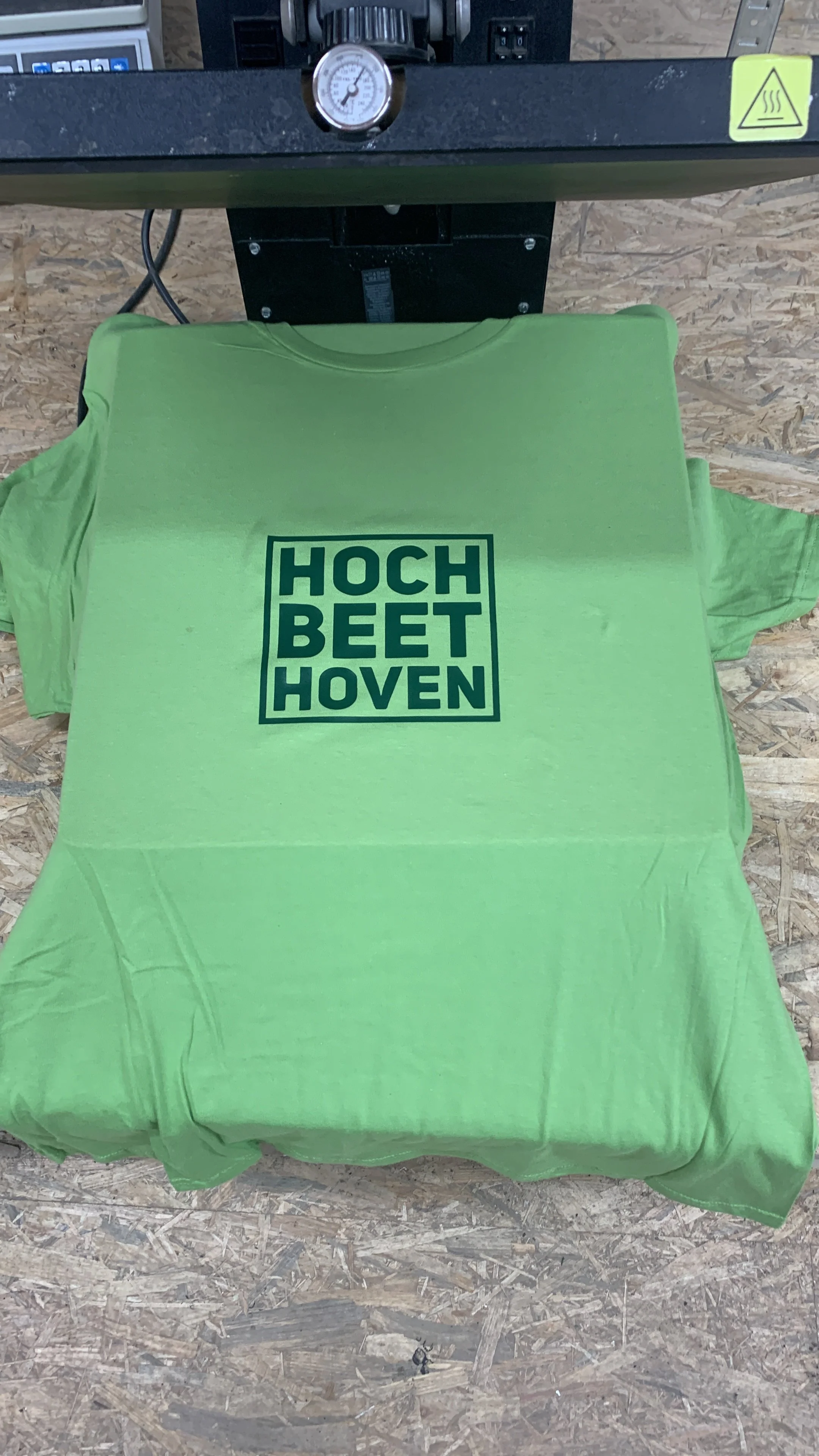 grünes T-Shirt mit schwarzem Text "HOCH BEET HOVEN" auf einem Druckgerät