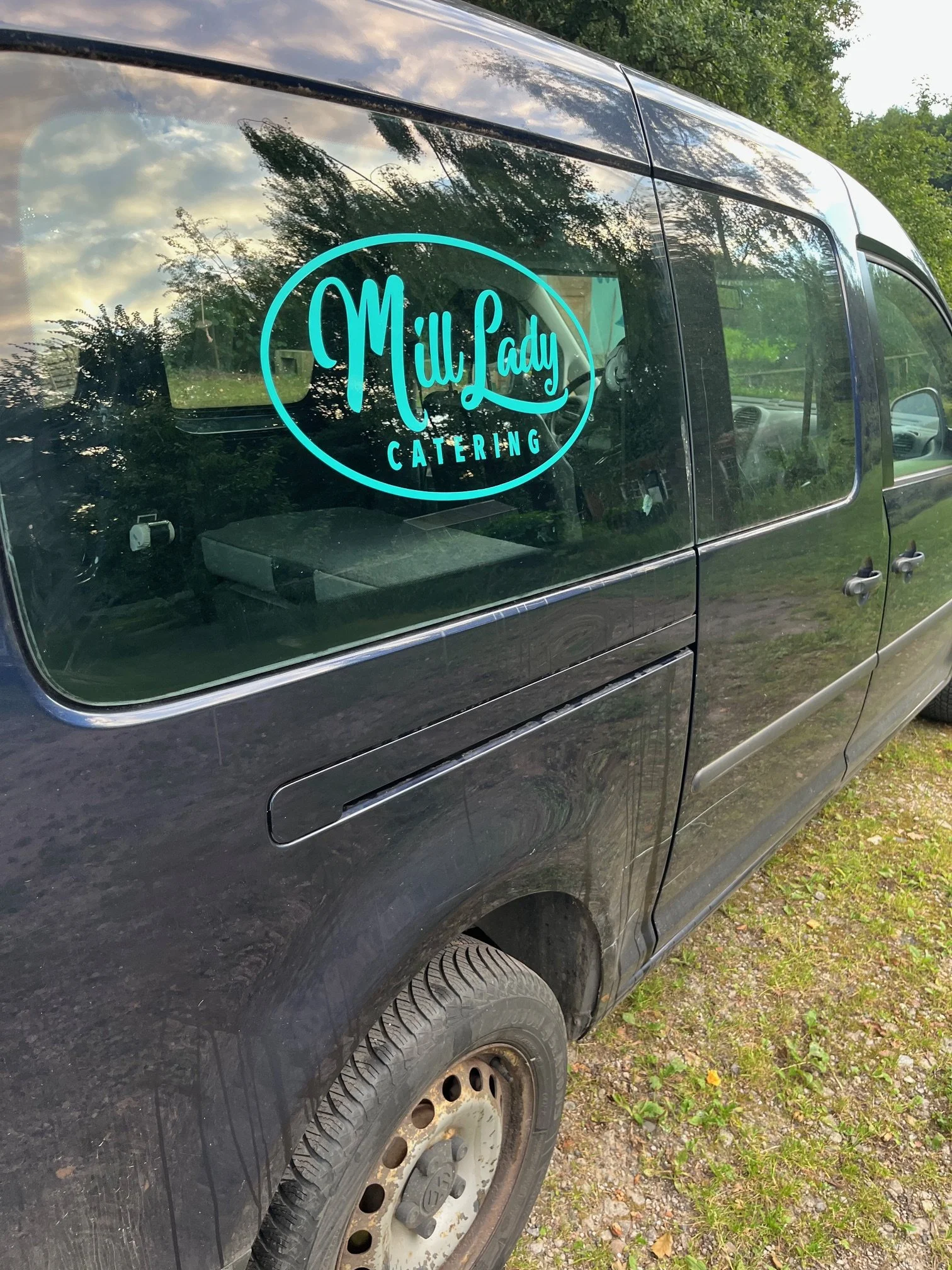 Fahrzeug mit einem Aufkleber, der 'MillLady Catering' heißt, auf der Seitenscheibe.