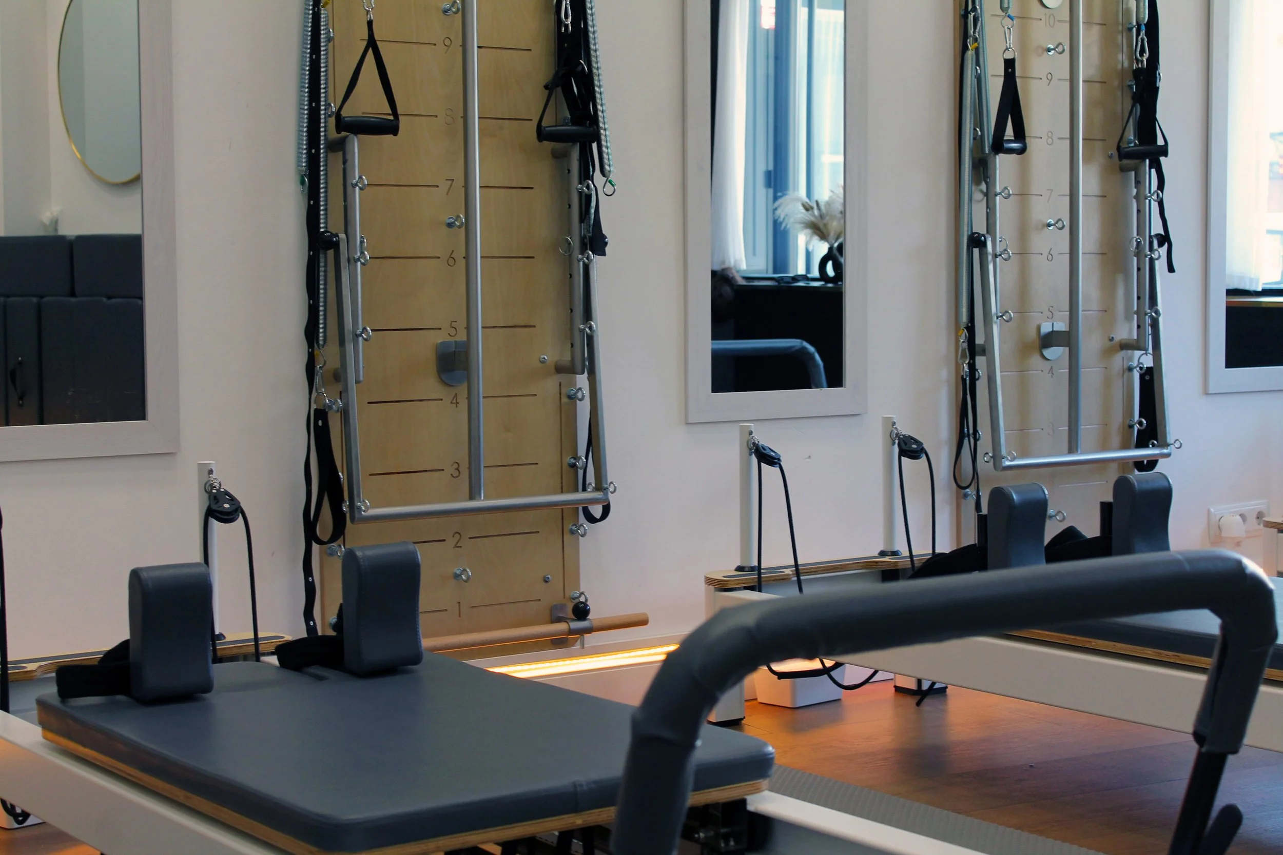 Sala mixta de reformer y springboard con aparatos de entrenamiento y espejos en las paredes.
