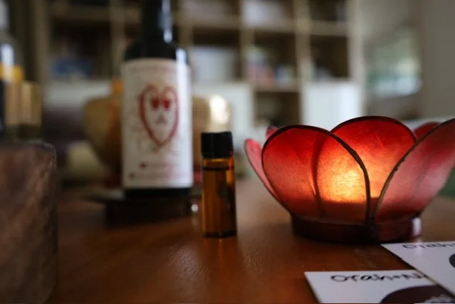 Ambiance de séance d'hypnose chez Orah Nes Sens : bougie allumée et bouteille d'eau informée par des formes géométriques sacrées pour le bien-être.

