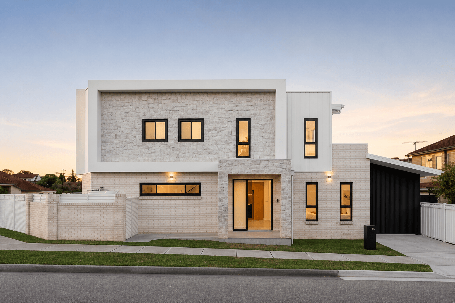 Modern two-story house with white brick and stone exterior, black-framed windows, and a small front yard with a sidewalk.