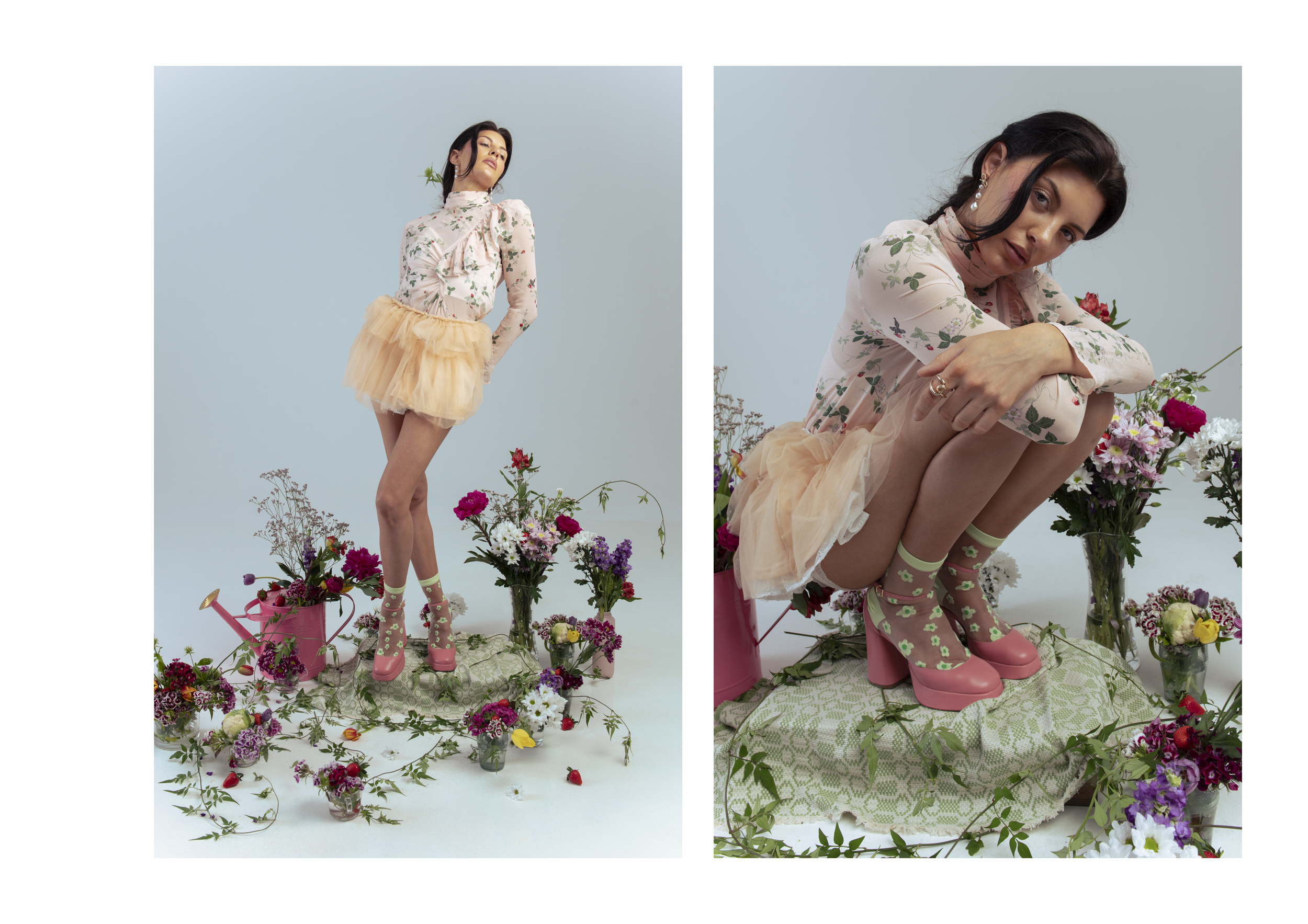 A woman in a floral dress with a peach tulle skirt stands and sits among numerous flowers and plants, with a light blue background.