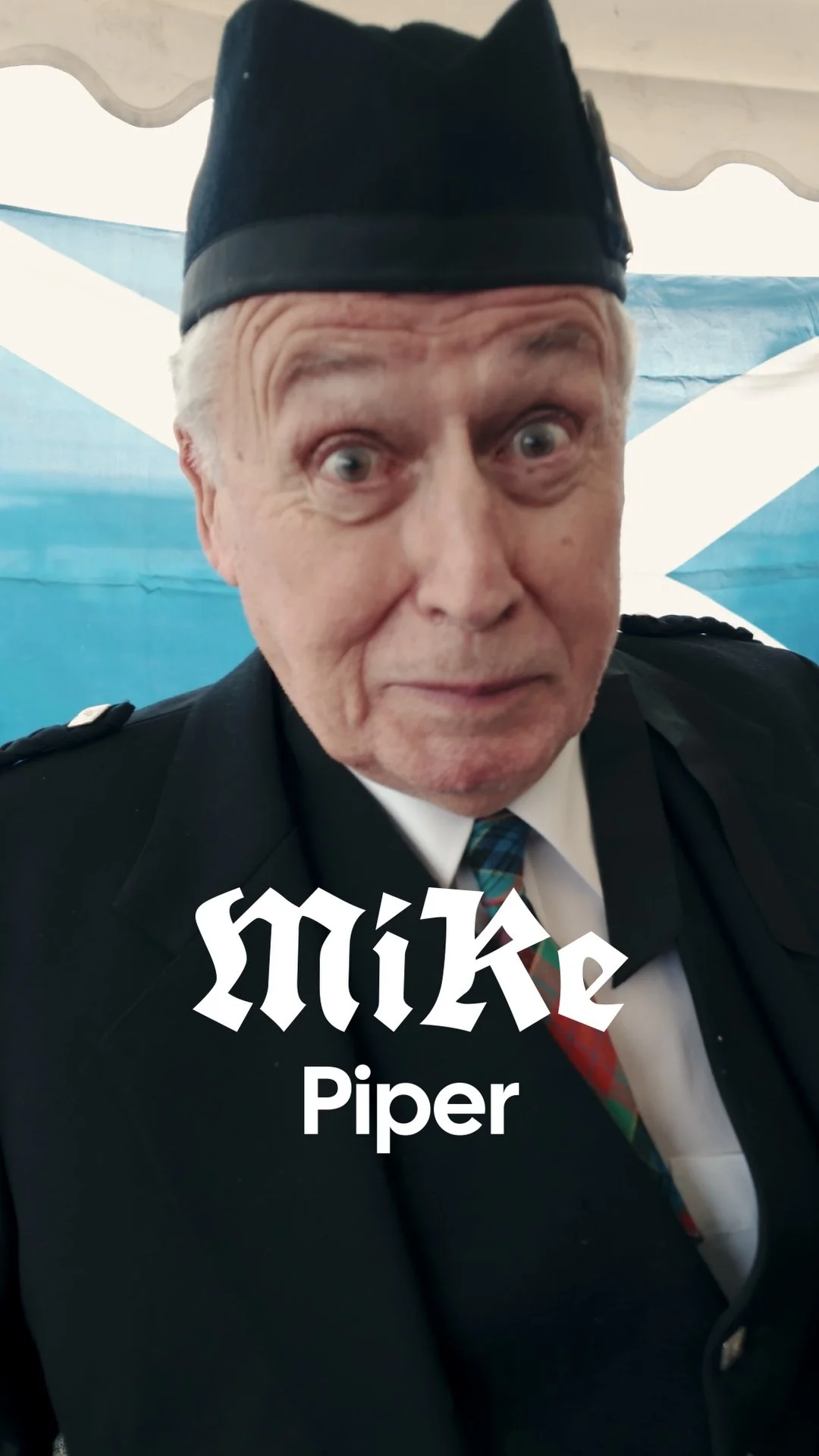 A man dressed as a police officer wearing a black hat and uniform, with a Scottish flag in the background, and text overlay that reads 'Mick Piper'.