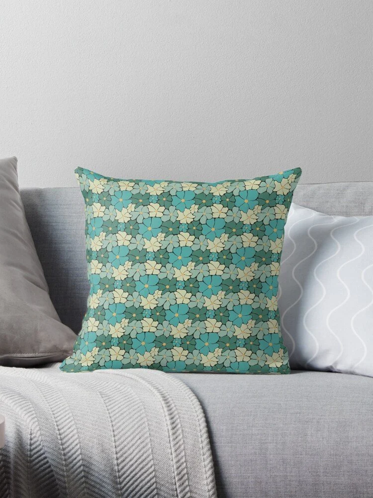 Decorative pillow with a flower power-inspired pattern of blue and cream-colored flowers on a light-colored sofa.