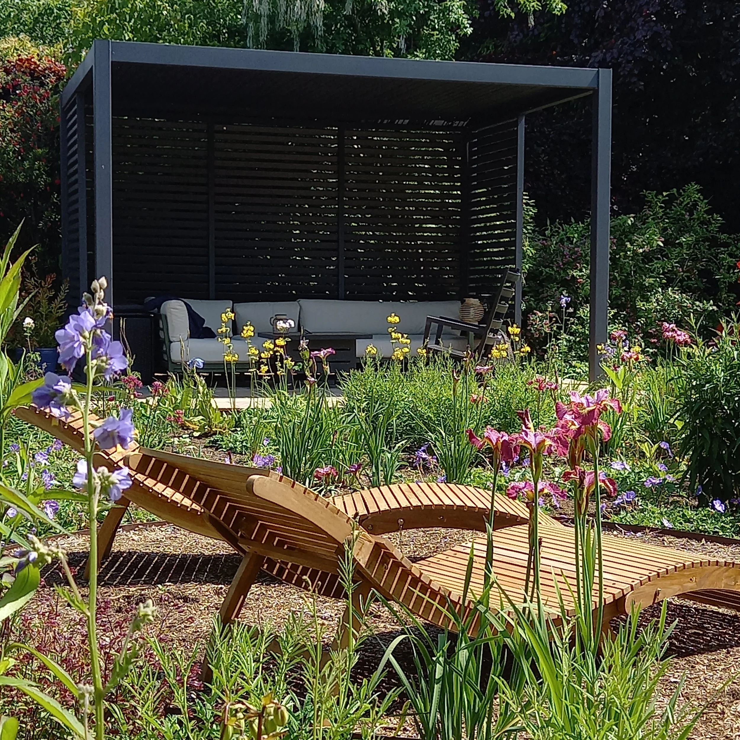 Image of a colourful meadow with a pergola and two sun loungers
