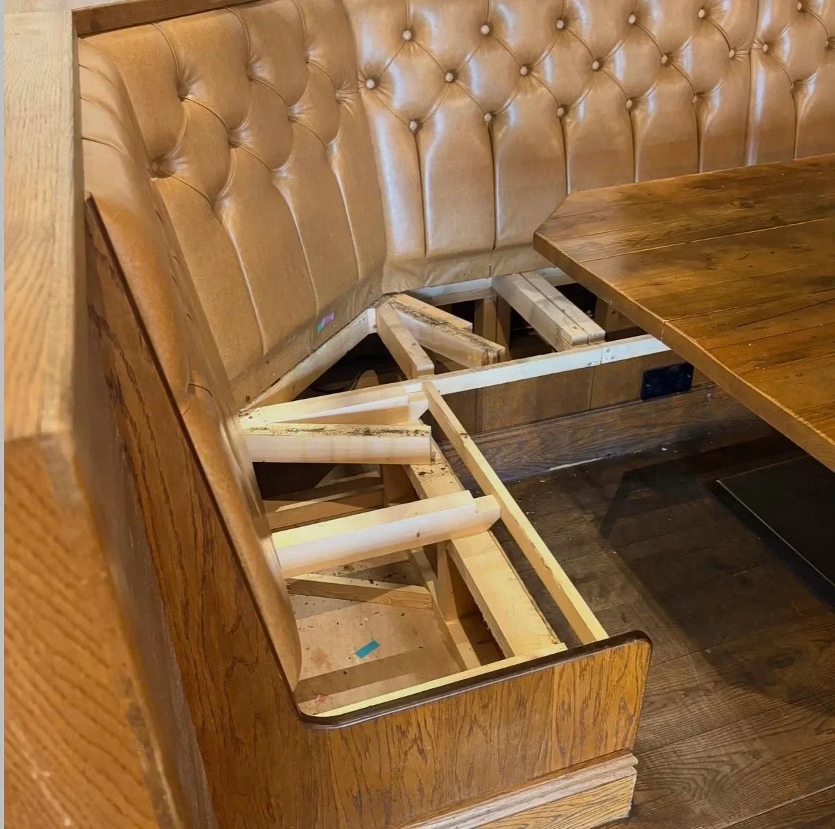 Exposed wooden frame beneath button-tufted leather banquette seating at The Beeswing in Kettering.