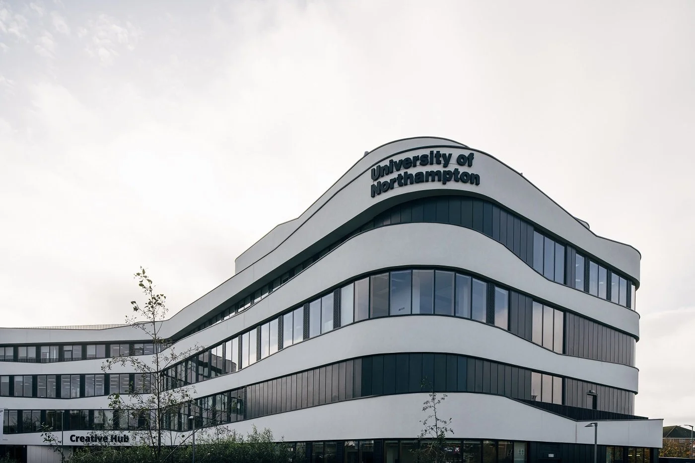 Modern university building with curved white and black exterior, with the sign 'University of Northampton' at the top.
