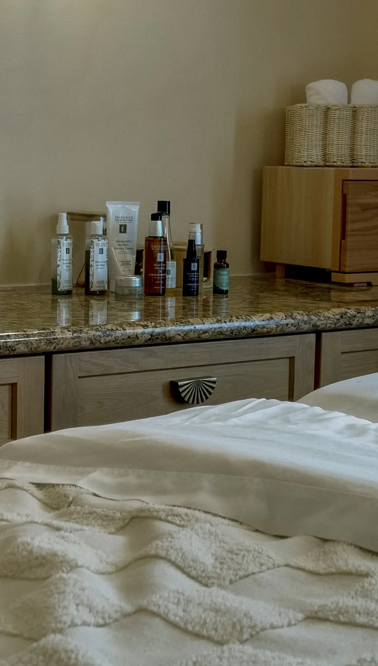 Calm neutral interior with white bedding and natural skincare products.