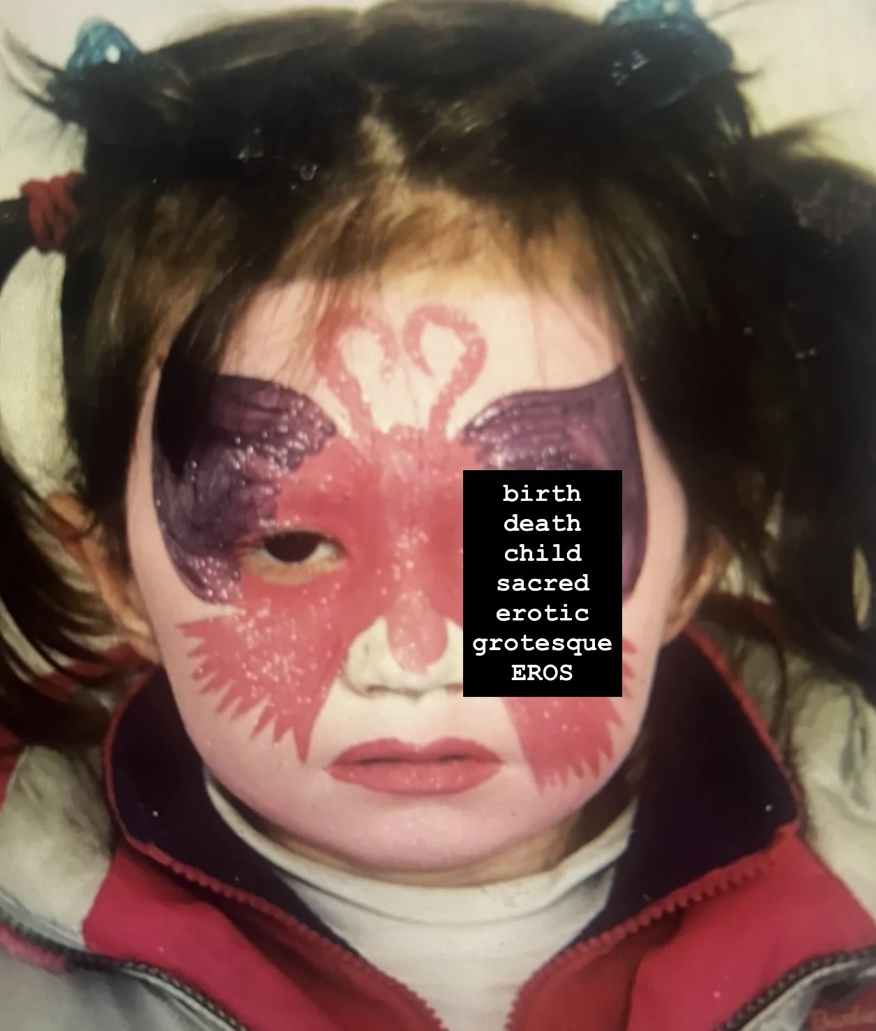 Child with face painted as a butterfly in red and purple, wearing a red jacket with a white shirt underneath.