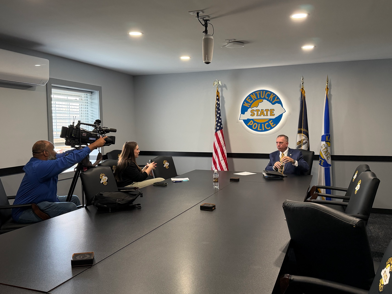 Kentucky State Police conference room with the KSP seal and flags displayed behind the meeting table.