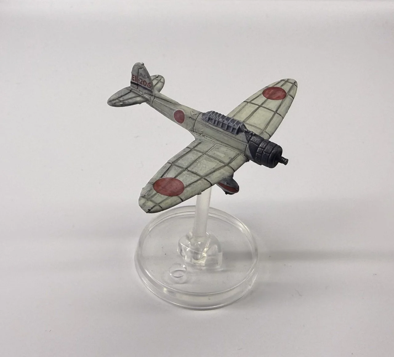 A model of a vintage Japanese fighter plane with red circles on the wings and fuselage, mounted on a clear stand against a plain background.