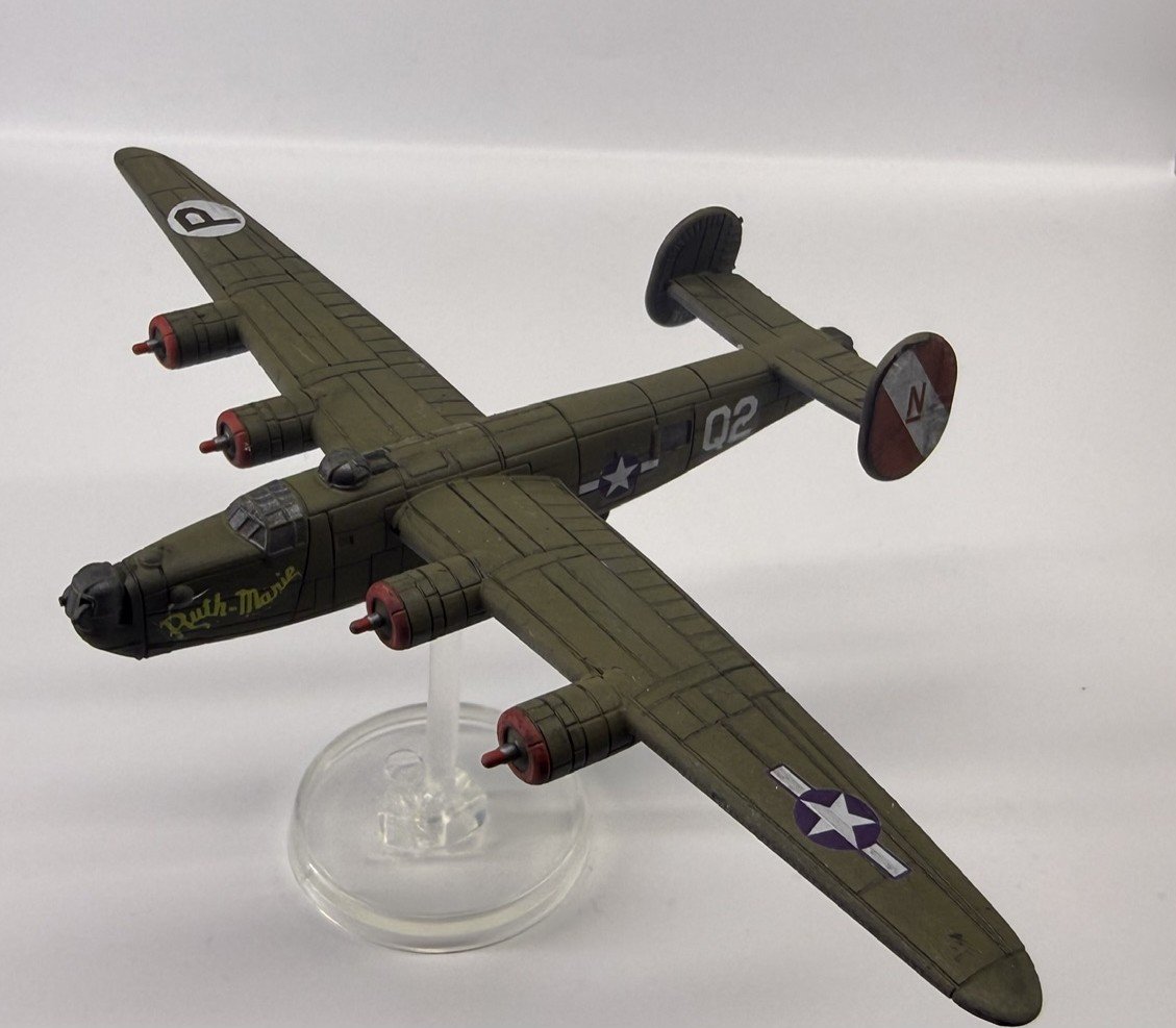Model of a military aircraft with green body, four engines, and twin tails, displayed on a clear stand against a plain white background.