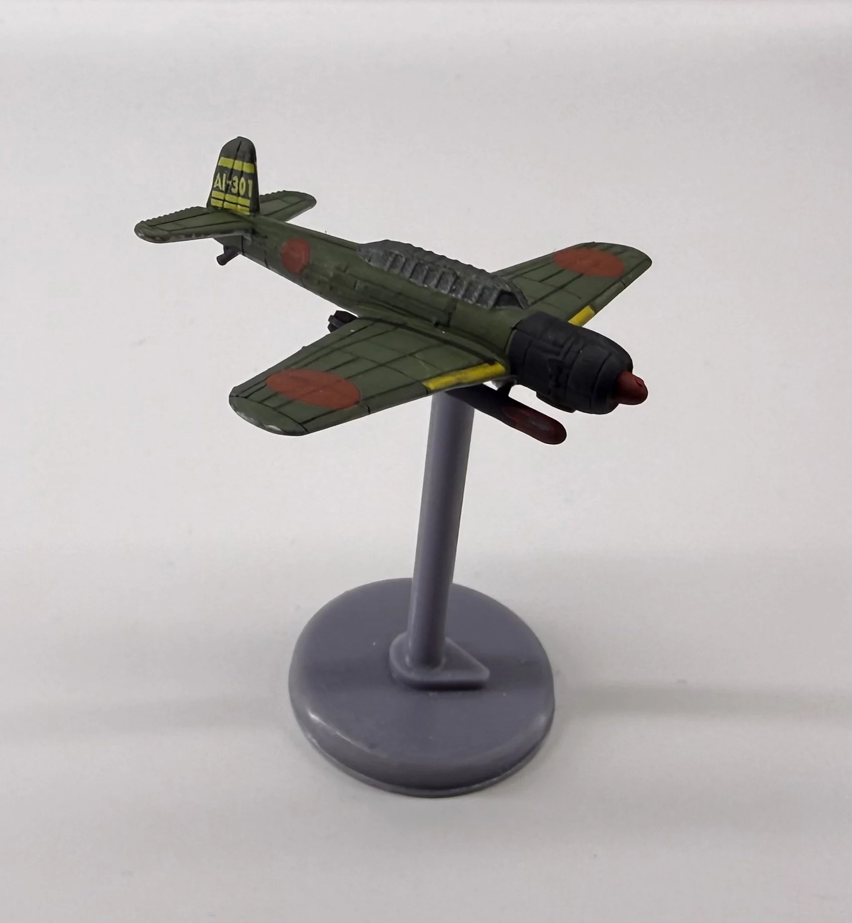 Model of a Japanese military aircraft with green camouflage, red circles on wings and fuselage, displayed on a stand.