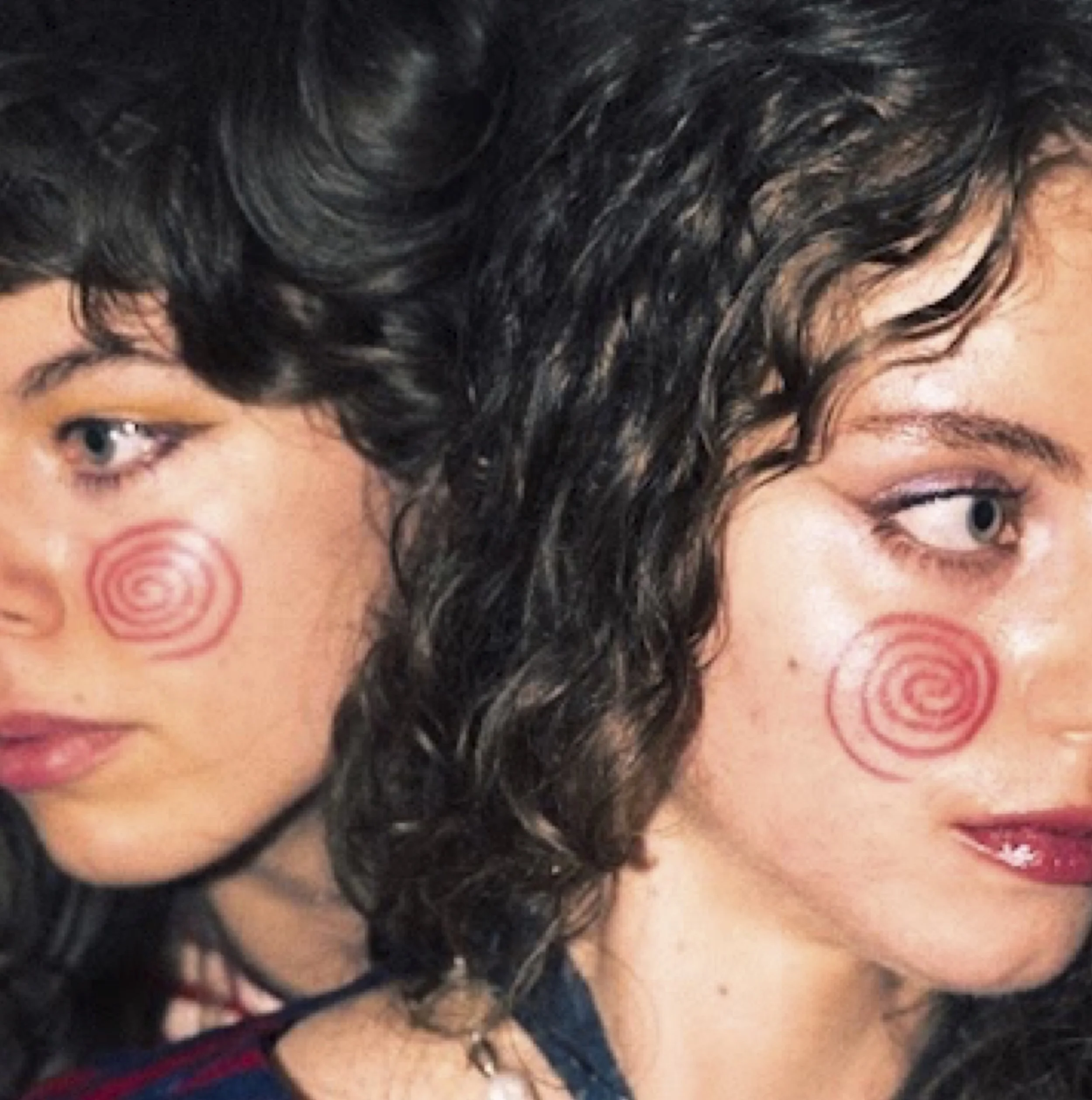 Close-up of two people facing away from each other with red spiral symbols on cheeks.