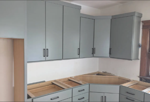 Kitchen cabinets being installed, with open drawer and cabinet doors, during a renovation.