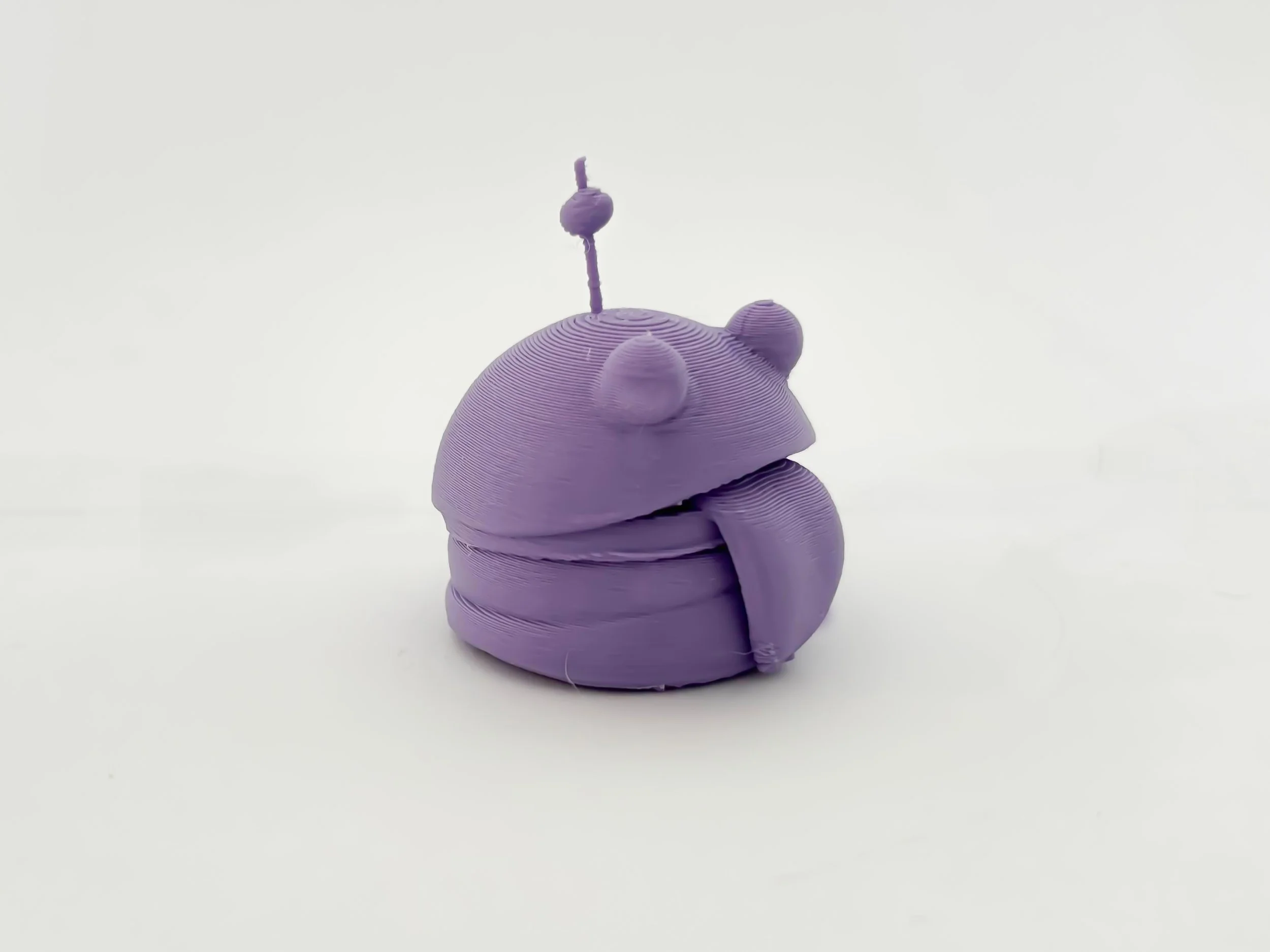 3D-Print of a burger unwrapped purple 3D-printed model of a tardigrade, a microscopic creature, on a white background.